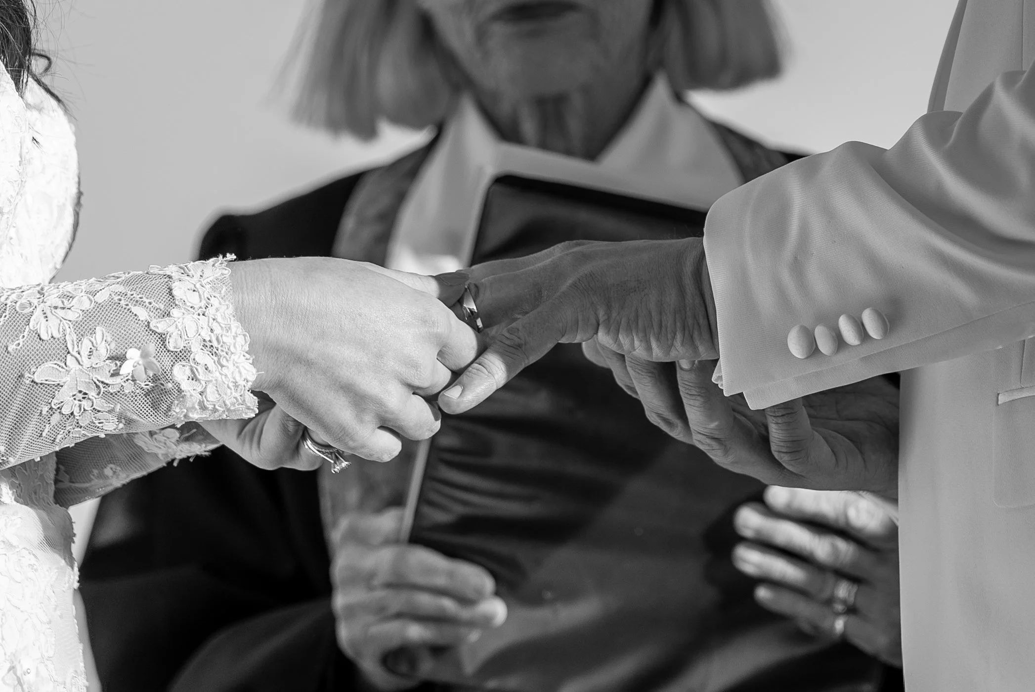 Close-up of a couple holding hands during a wedding ceremony, with an officiant standing behind them during a wedding at Red Jacket Resort in Cape Cod. 