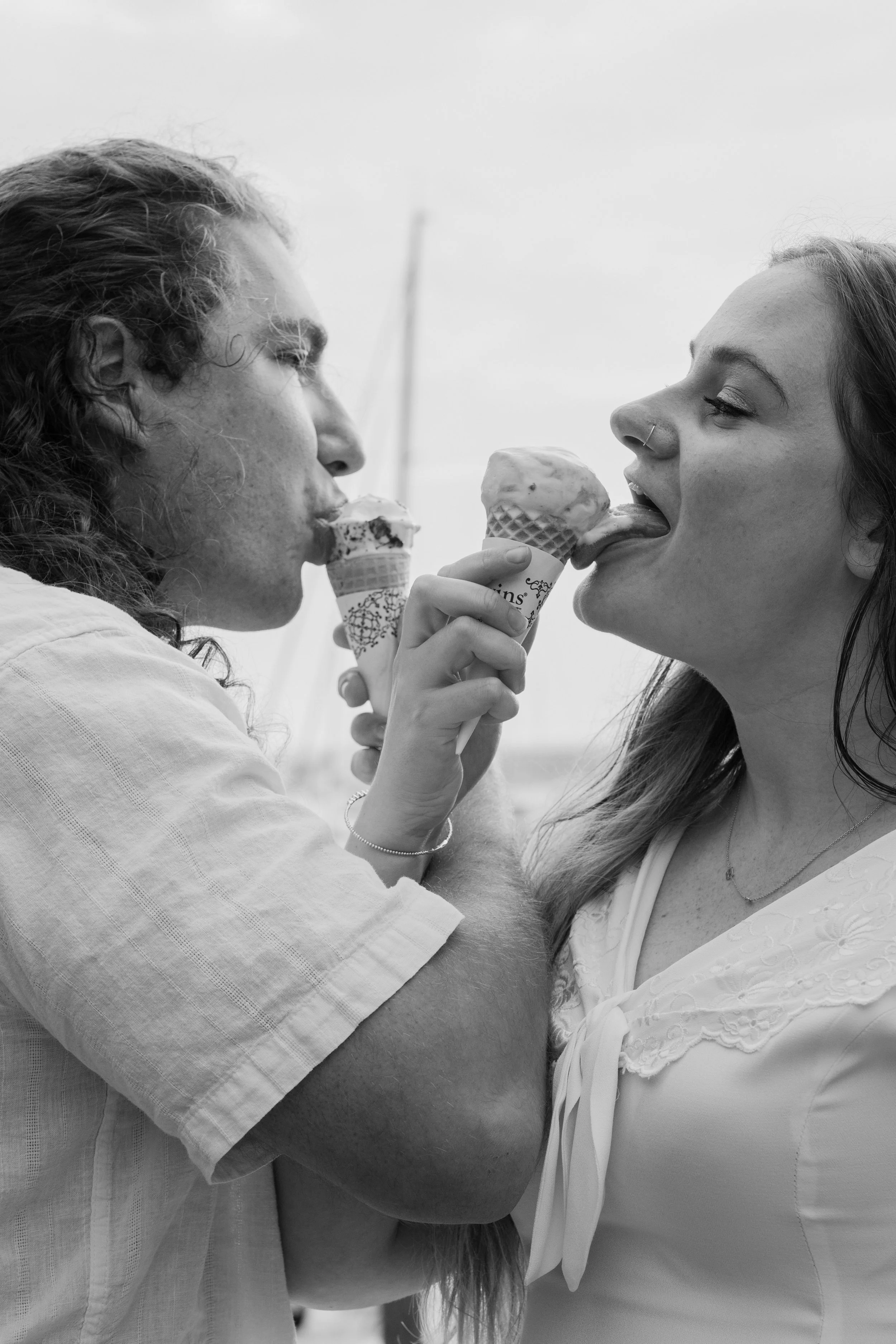 Two people sharing ice cream cones outdoors, close-up, black and white photo after an elopement at Beavertail State Park in Rhode Island. 