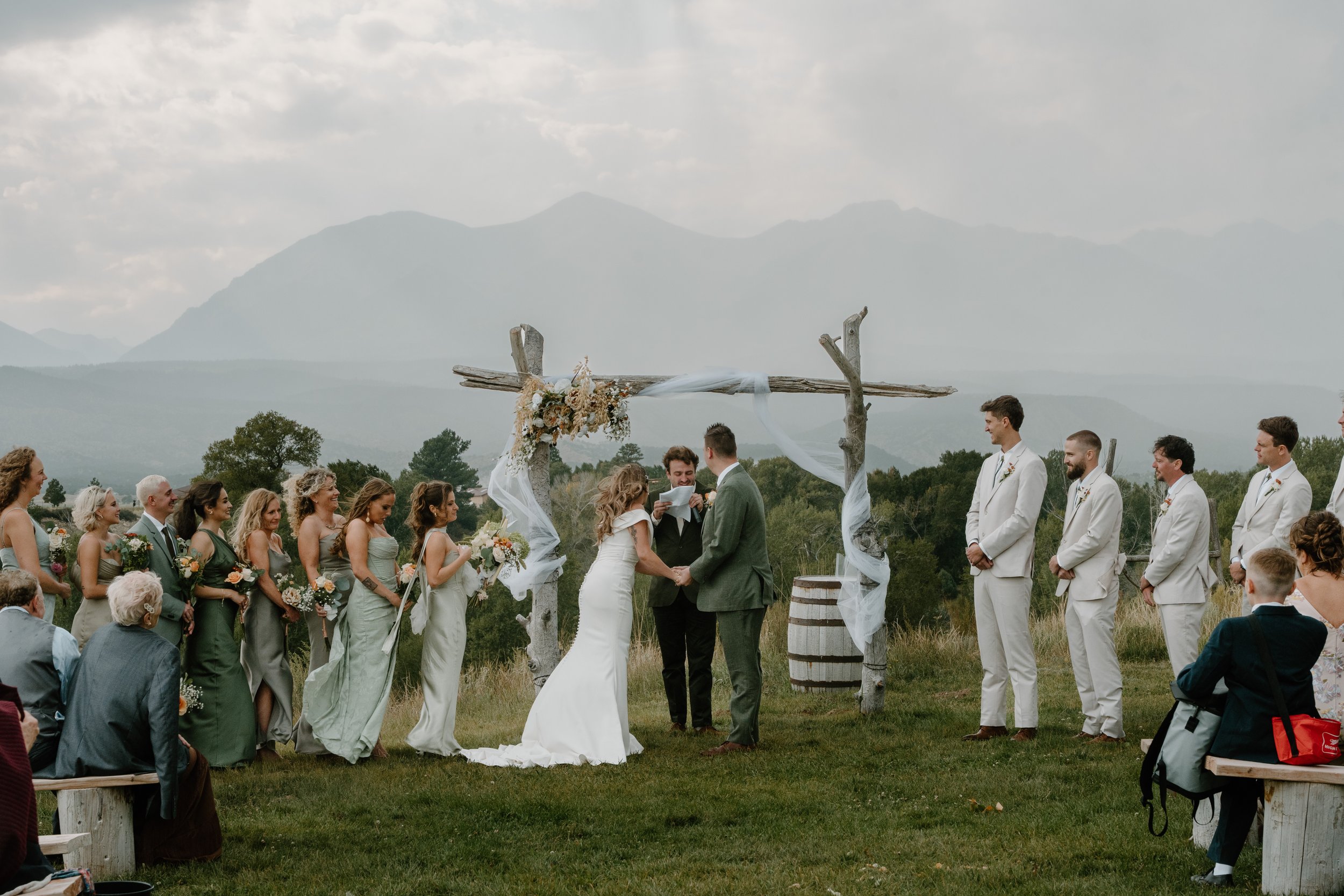 A wedding ceremony outdoors with a bride and groom exchanging vows at Everett Ranch in Salida, Colorado.