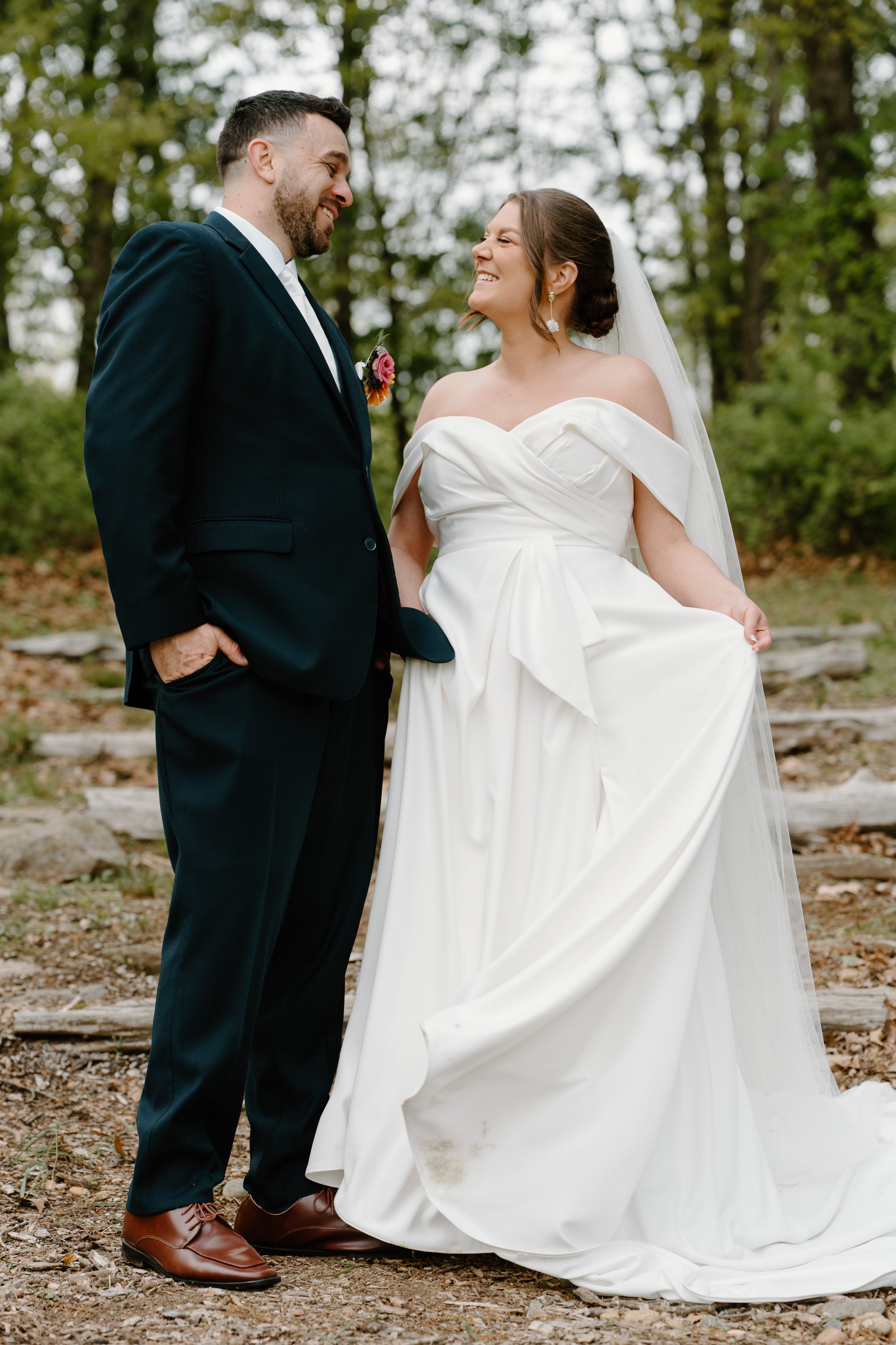 A bride and groom smiling at each other outdoors during their wedding, with trees and leaves behind them for a wedding at Holiday Hill Day Camp in Connecticut.