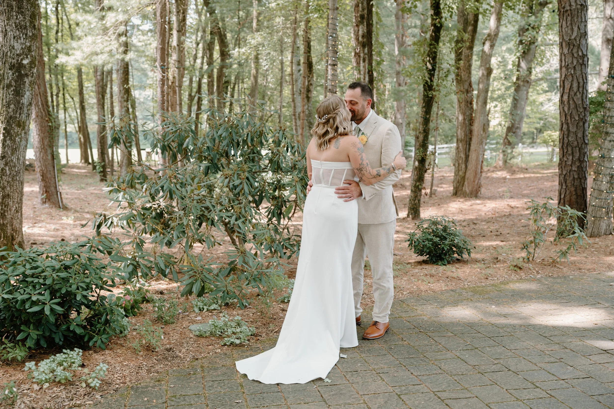 A bride and groom sharing a kiss outdoors in a wooded area for a wedding at Tunxis Country Club in Connecticut. 