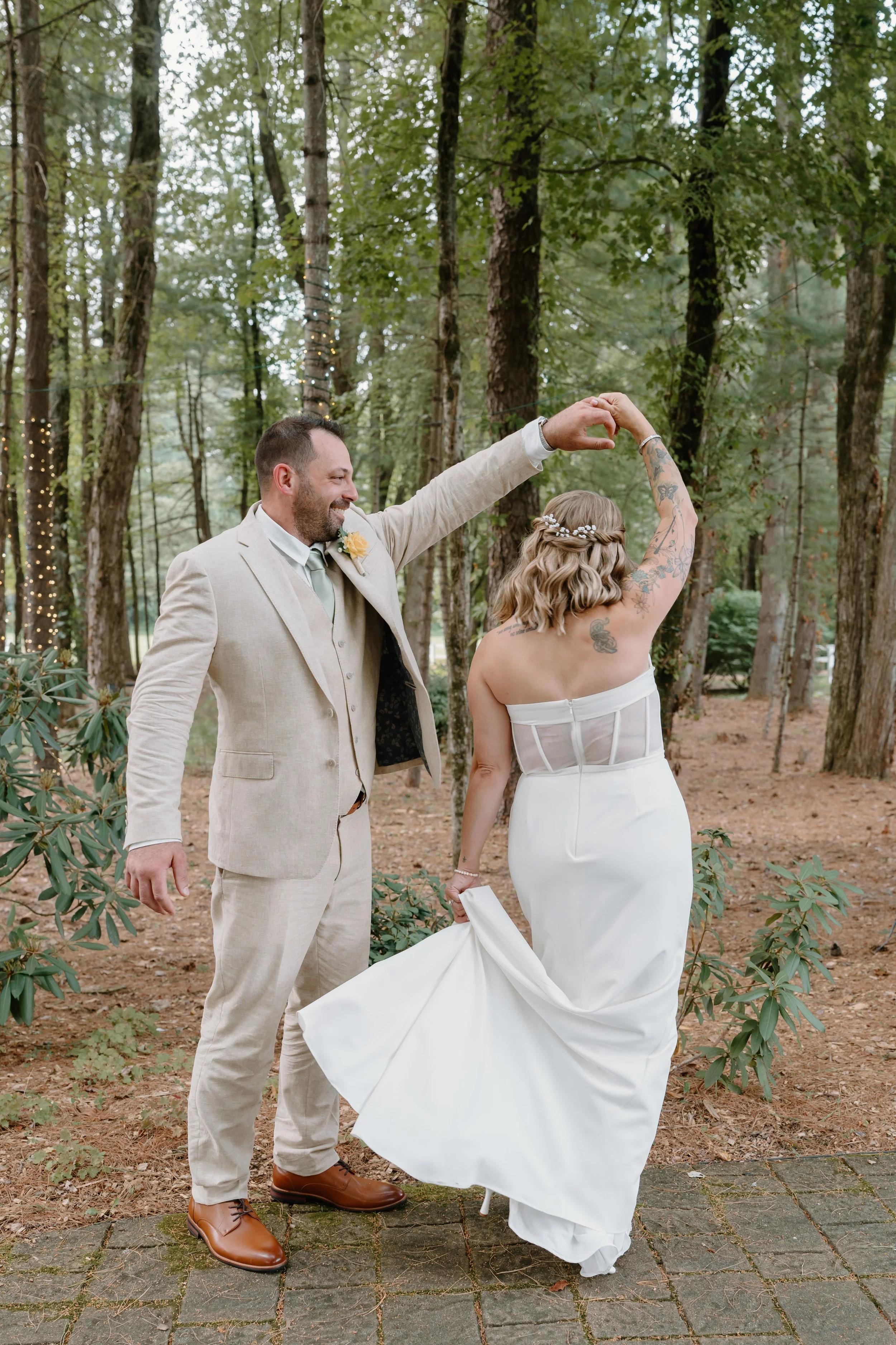 A newlywed couple dancing outdoors in a wooded area, with the groom spinning the bride for a wedding at Tunxis Country Club in Connecticut. 