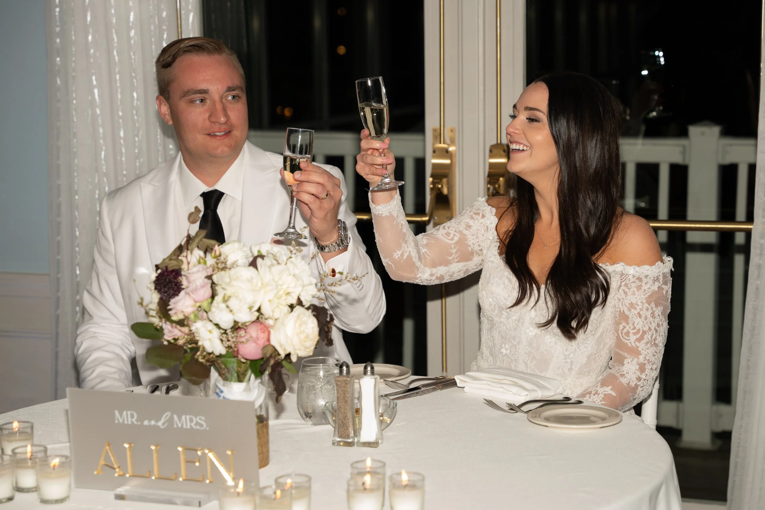 A newlywed couple celebrates at their wedding reception, raising glasses of champagne for a toast during a wedding at Red Jacket Resort in Cape Cod. 