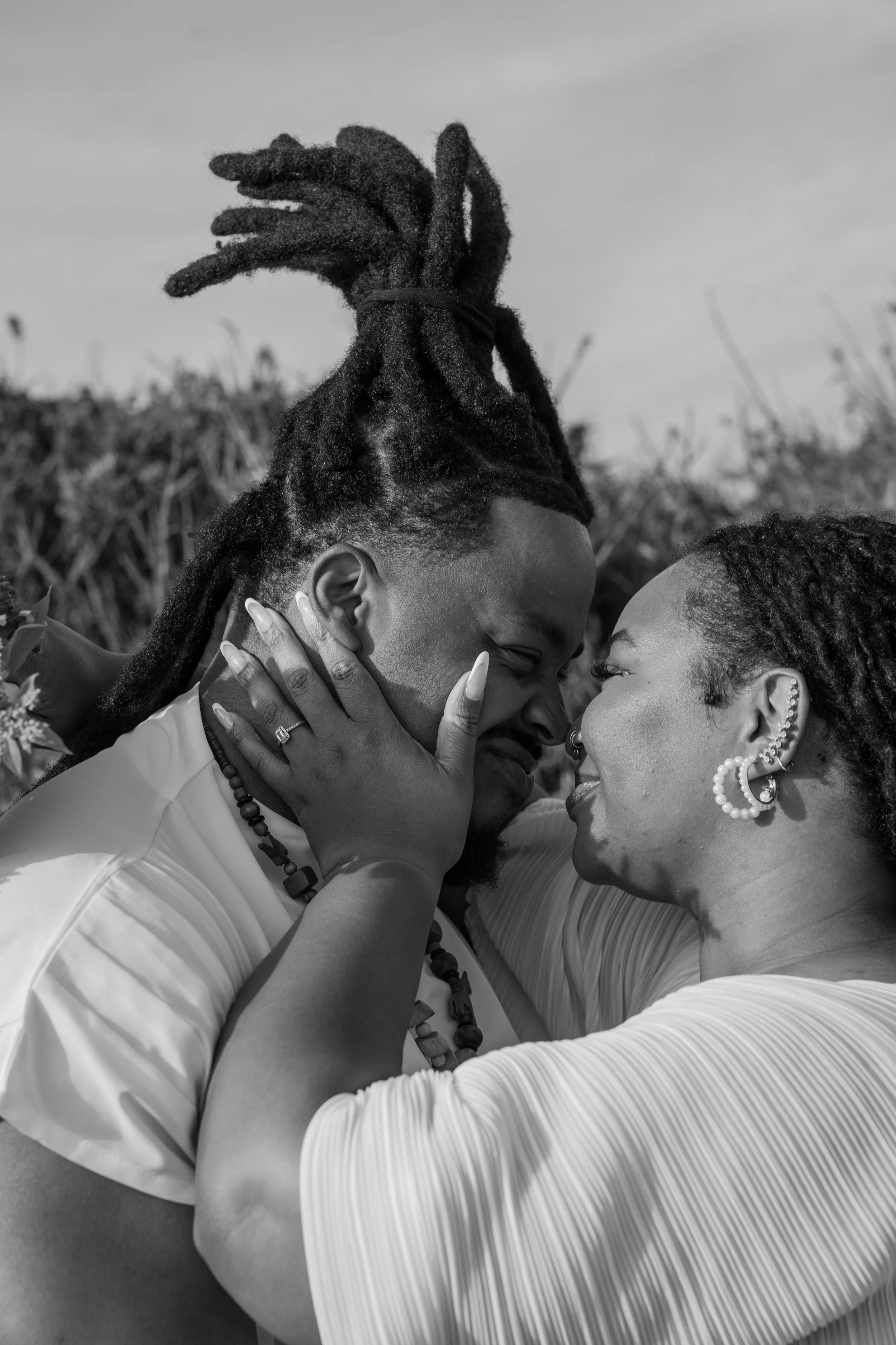 A black and white close-up photo of a couple touching foreheads and smiling, outdoors with a blurred natural background at an elopement at Second Beach in Rhode Island. 