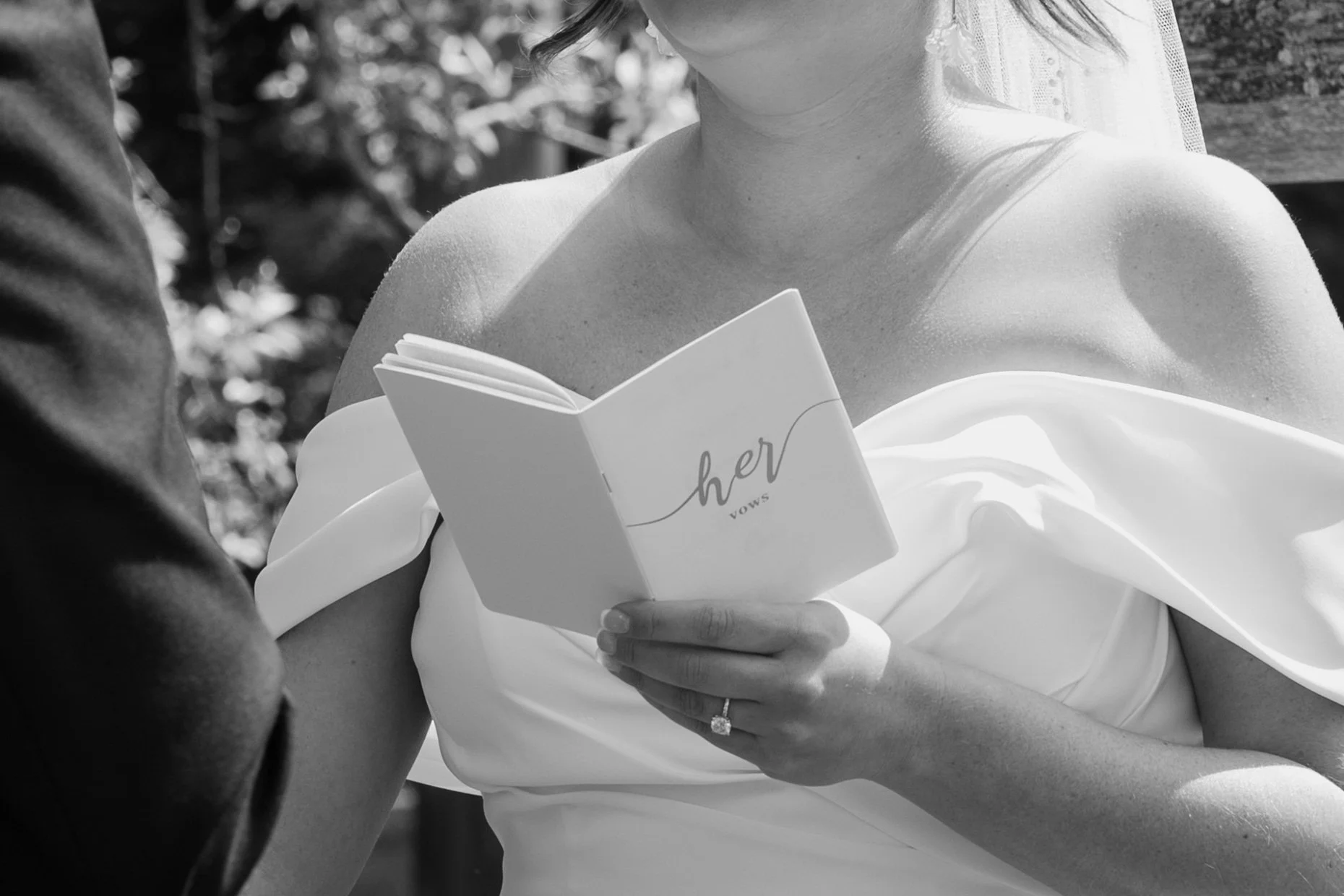 A bride with a wedding ring holding a vow book labeled 'her vows' during a wedding ceremony for a wedding at Holiday Hill Day Camp in Connecticut.
