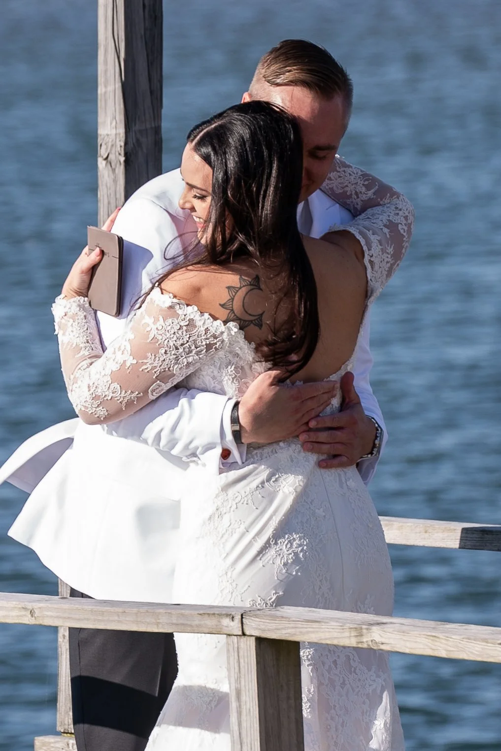 A newly married couple embracing on a dock by the water during a wedding at Red Jacket Resort in Cape Cod. 