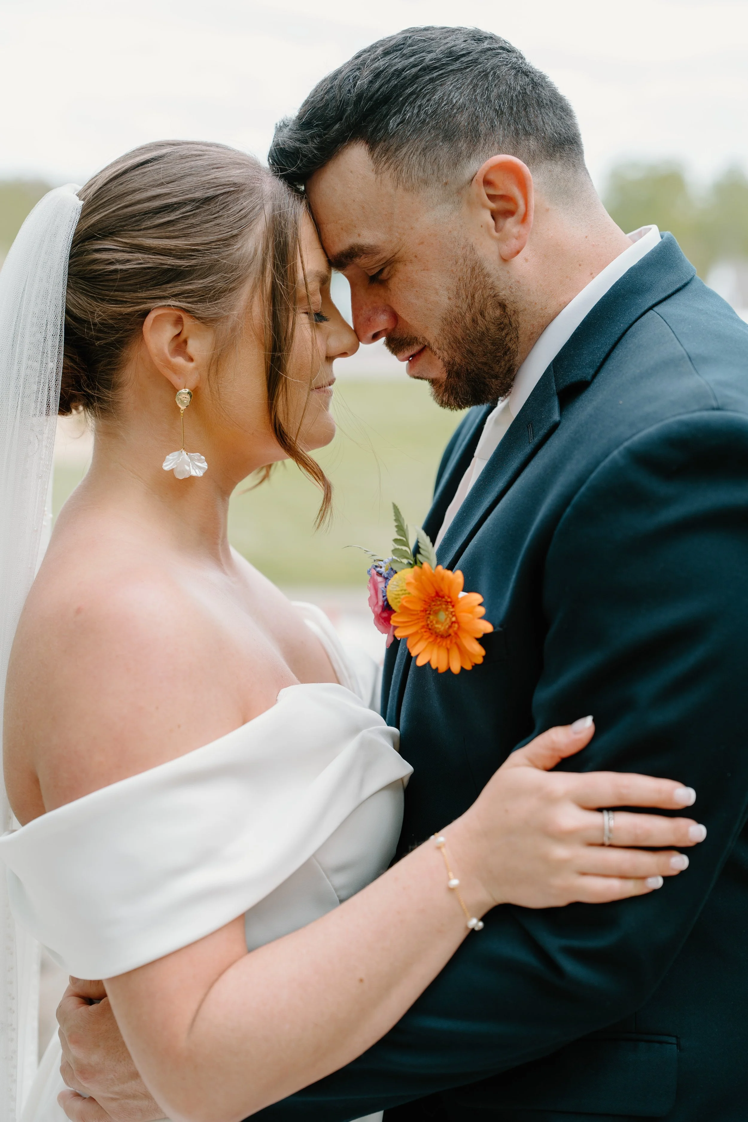 A bride and groom with foreheads touching in a romantic embrace, outdoors during their wedding at Holiday Hill Day Camp in Connecticut.