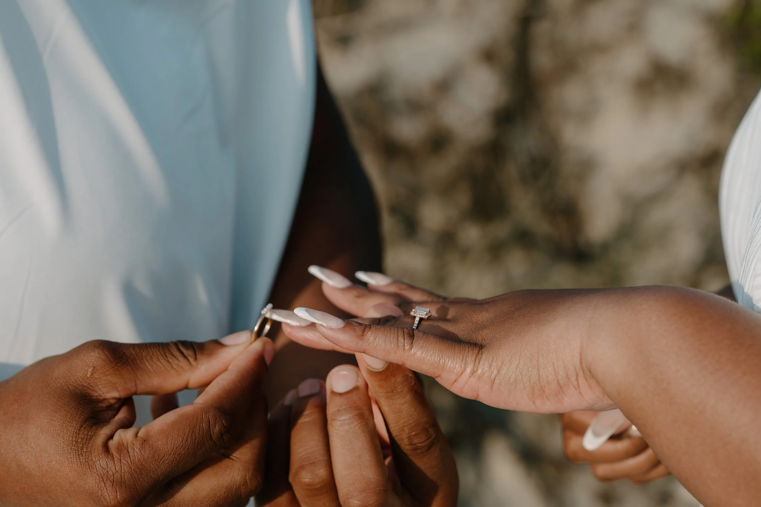 Close-up of two people exchanging rings, one is placing a ring on the other's finger at an elopement at Second Beach in Rhode Island. 