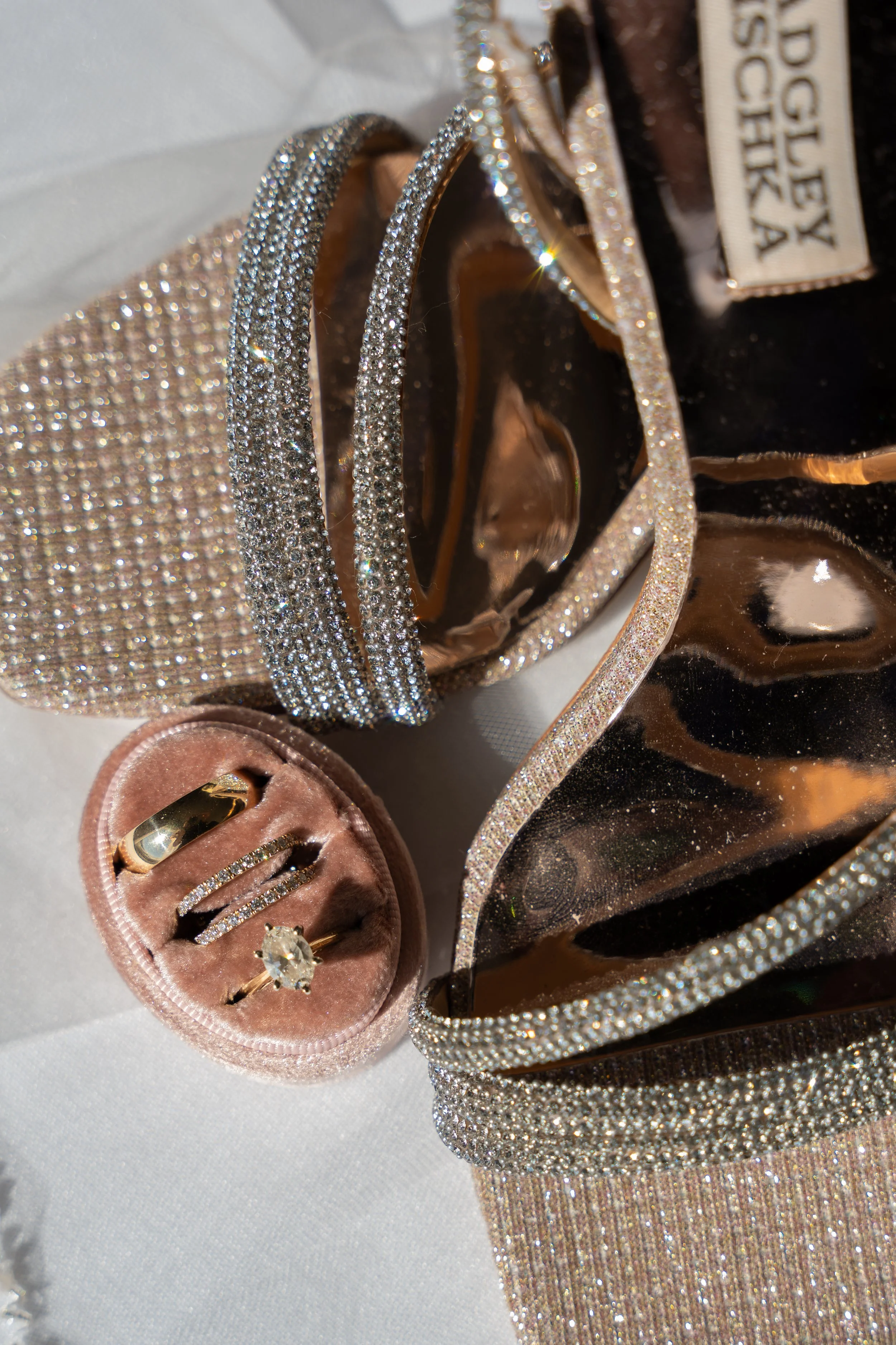 Jewelry display with rings, bracelets, and necklaces, all decorated with numerous small sparkling stones, set on a shiny, black and gold surface during a wedding at Red Jacket Resort in Cape Cod. 