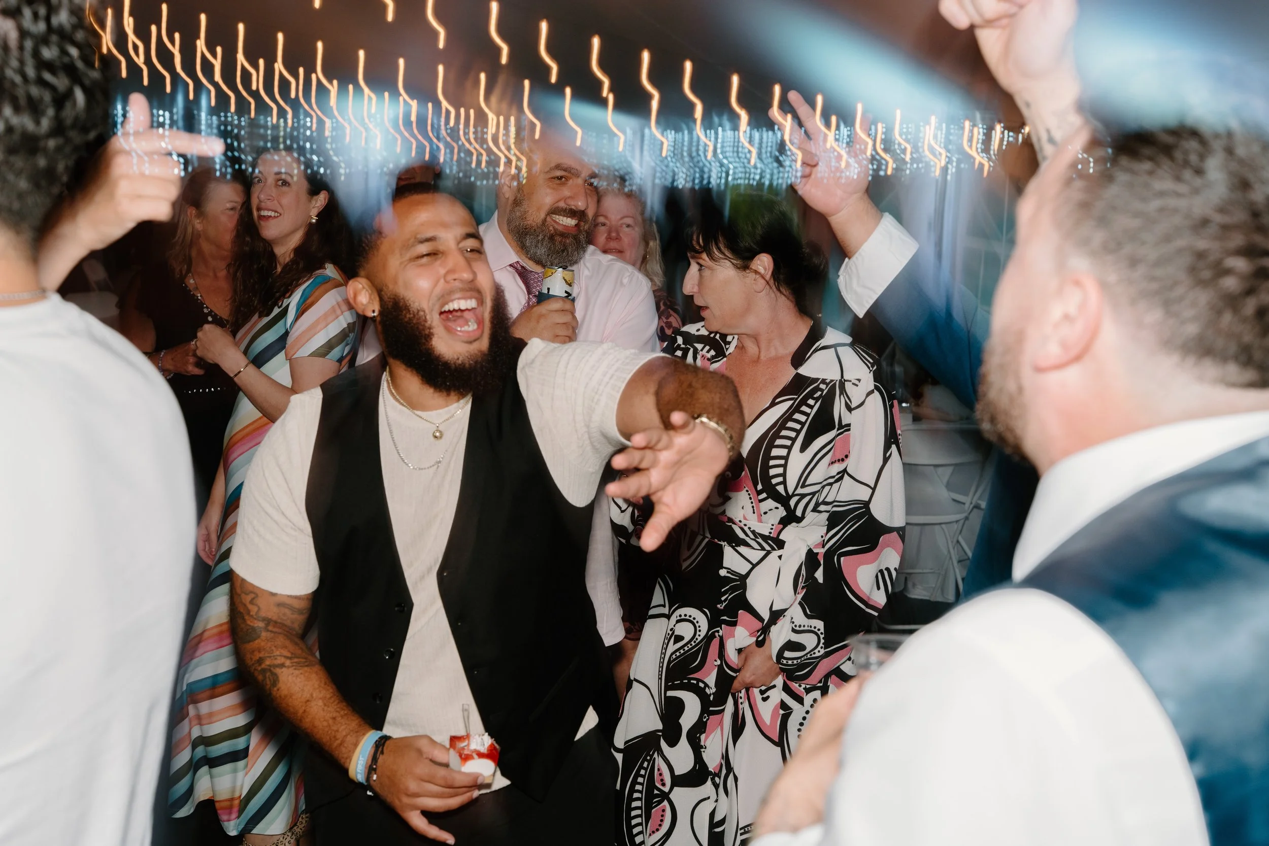 People dancing and celebrating at a party with colorful lights for a wedding at Holiday Hill Day Camp in Connecticut.
