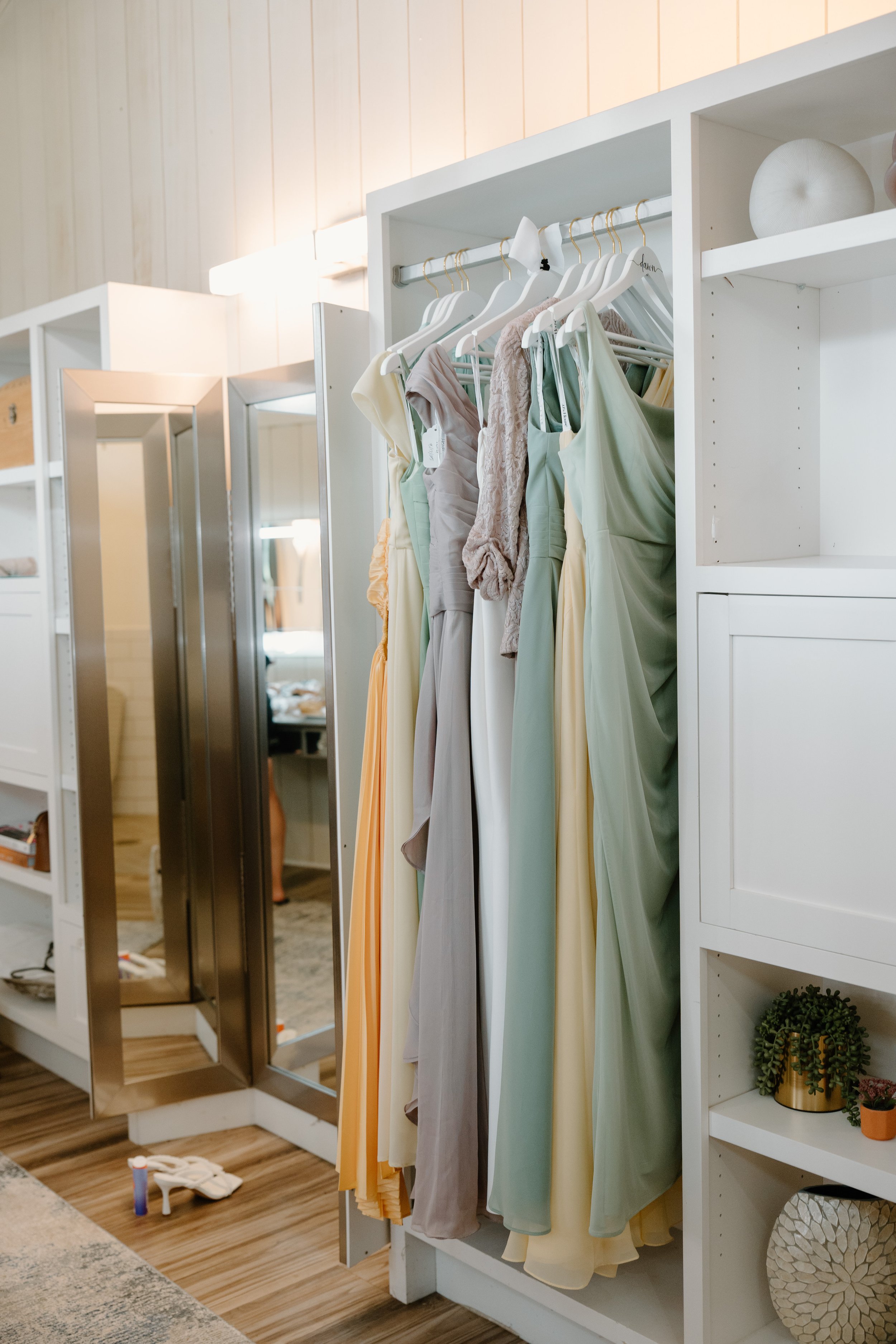 A white closet with dresses hanging on a rod and a mirror in the background for a wedding at Tunxis Country Club in Connecticut. 