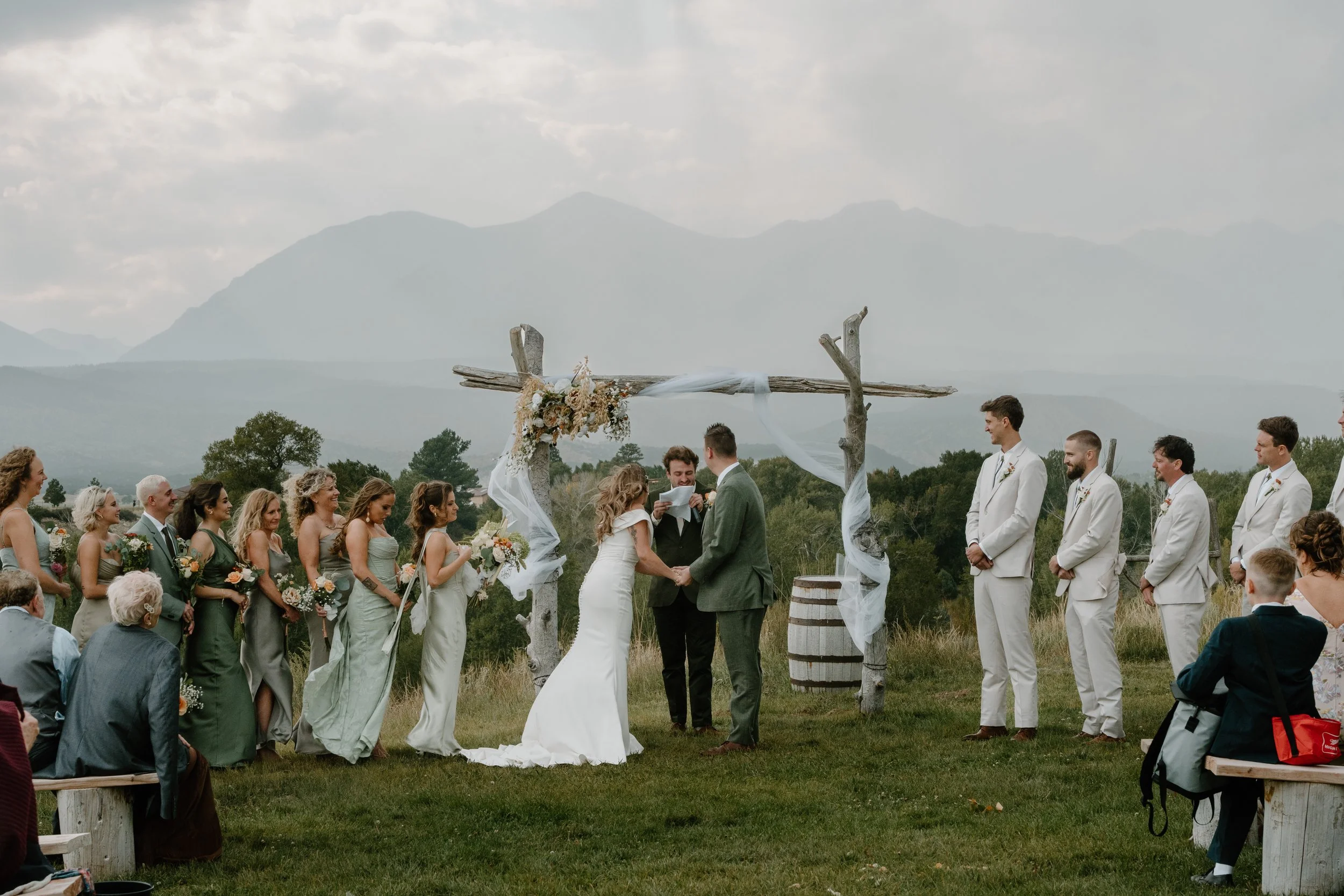 Wedding ceremony outdoors with a bride and groom holding hands in front of an officiant at Everett Ranch in Salida, Colorado.
