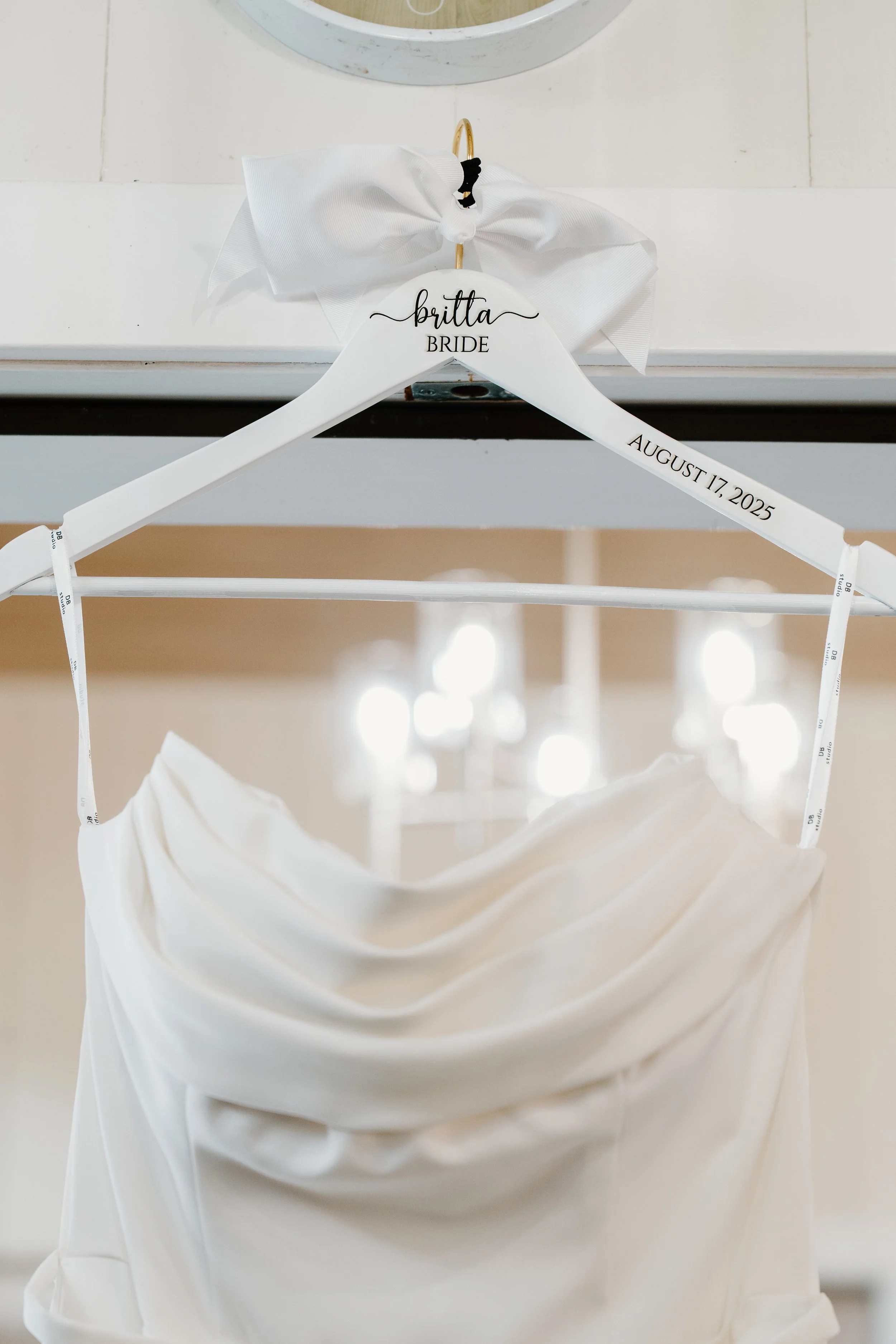 White wedding dress on a hanger hung on a white hook for a wedding at Tunxis Country Club in Connecticut. 