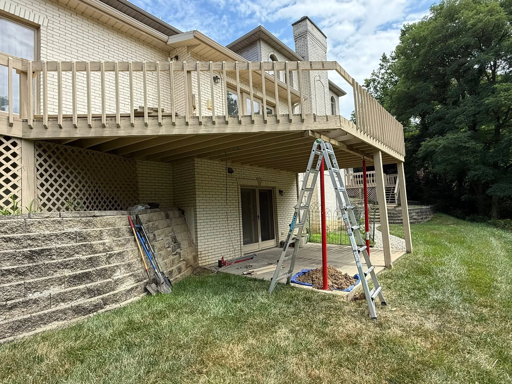 Deck support posts replaced — temporary jacks carry the deck while the old post comes out