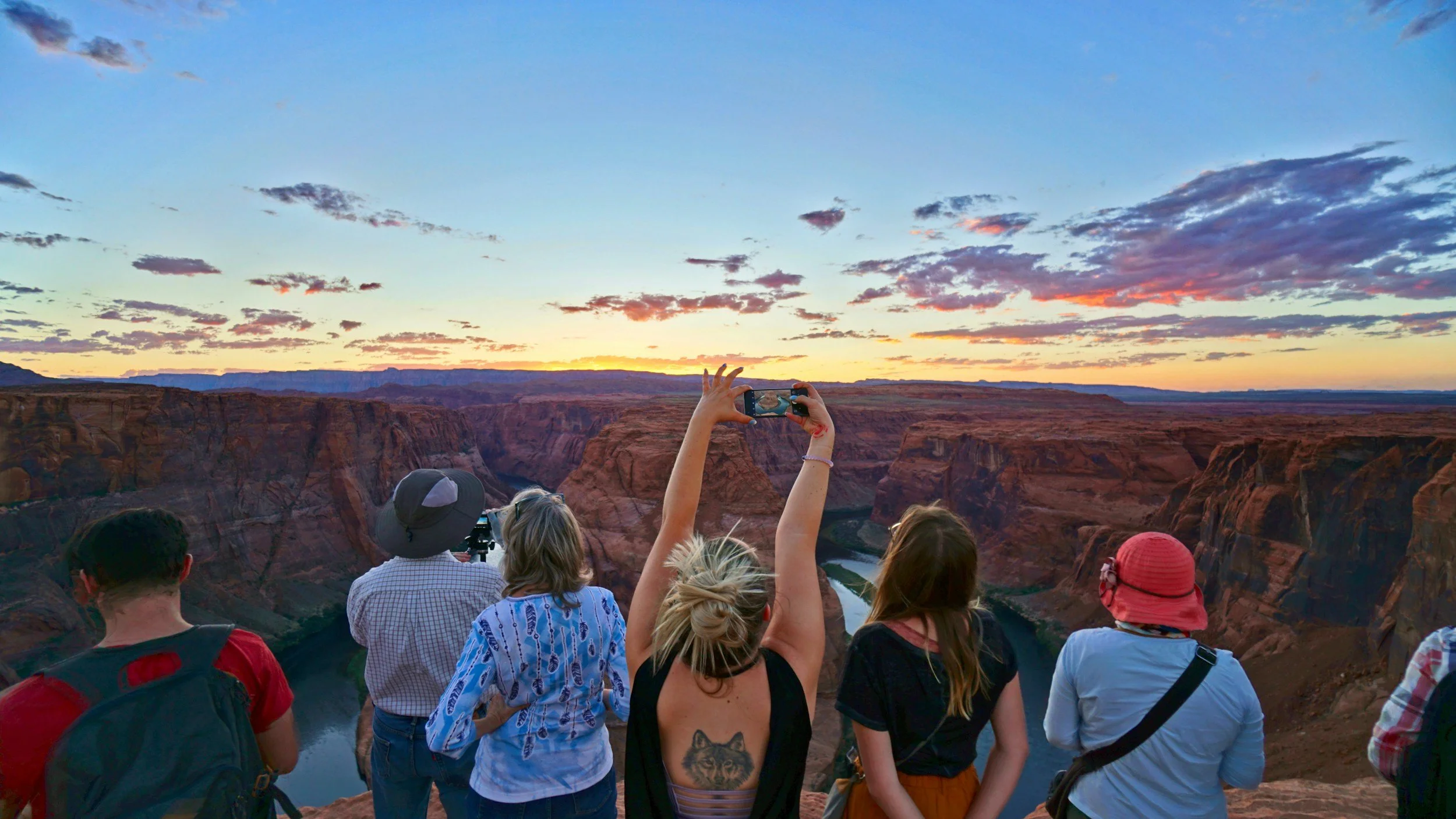 Group of tourists at the Grand Canyon taking photos during sunset.