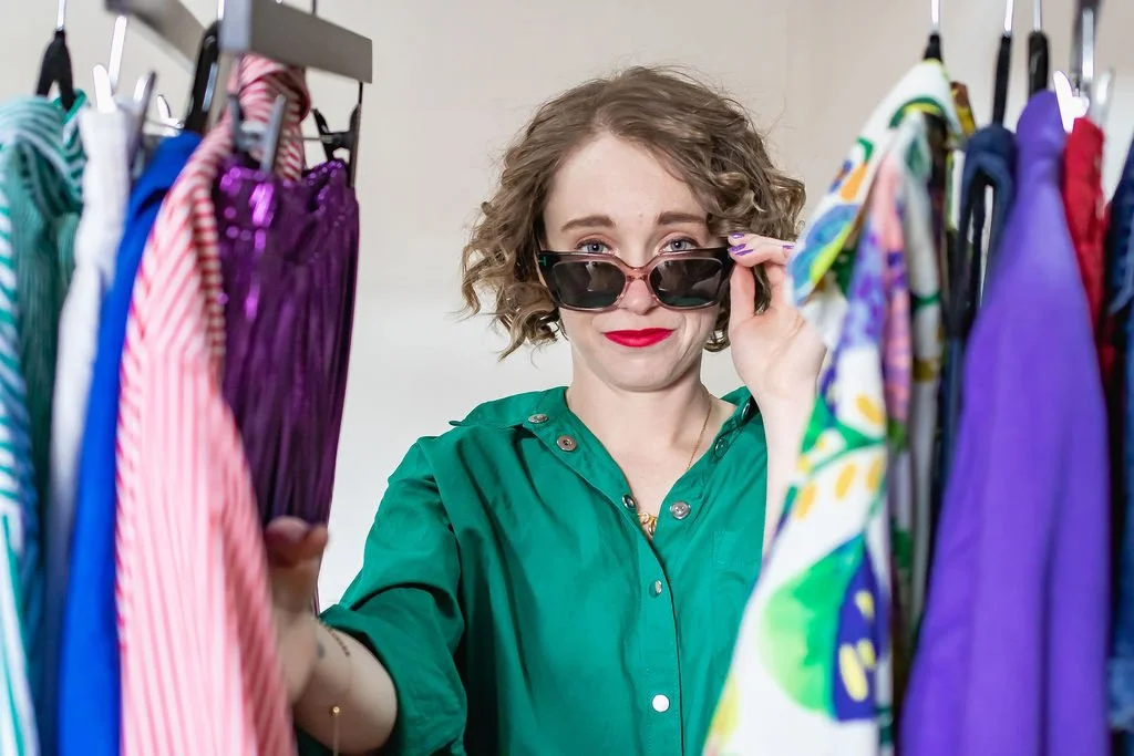 Megan pulling down sunglasses looking through a rack of clothes