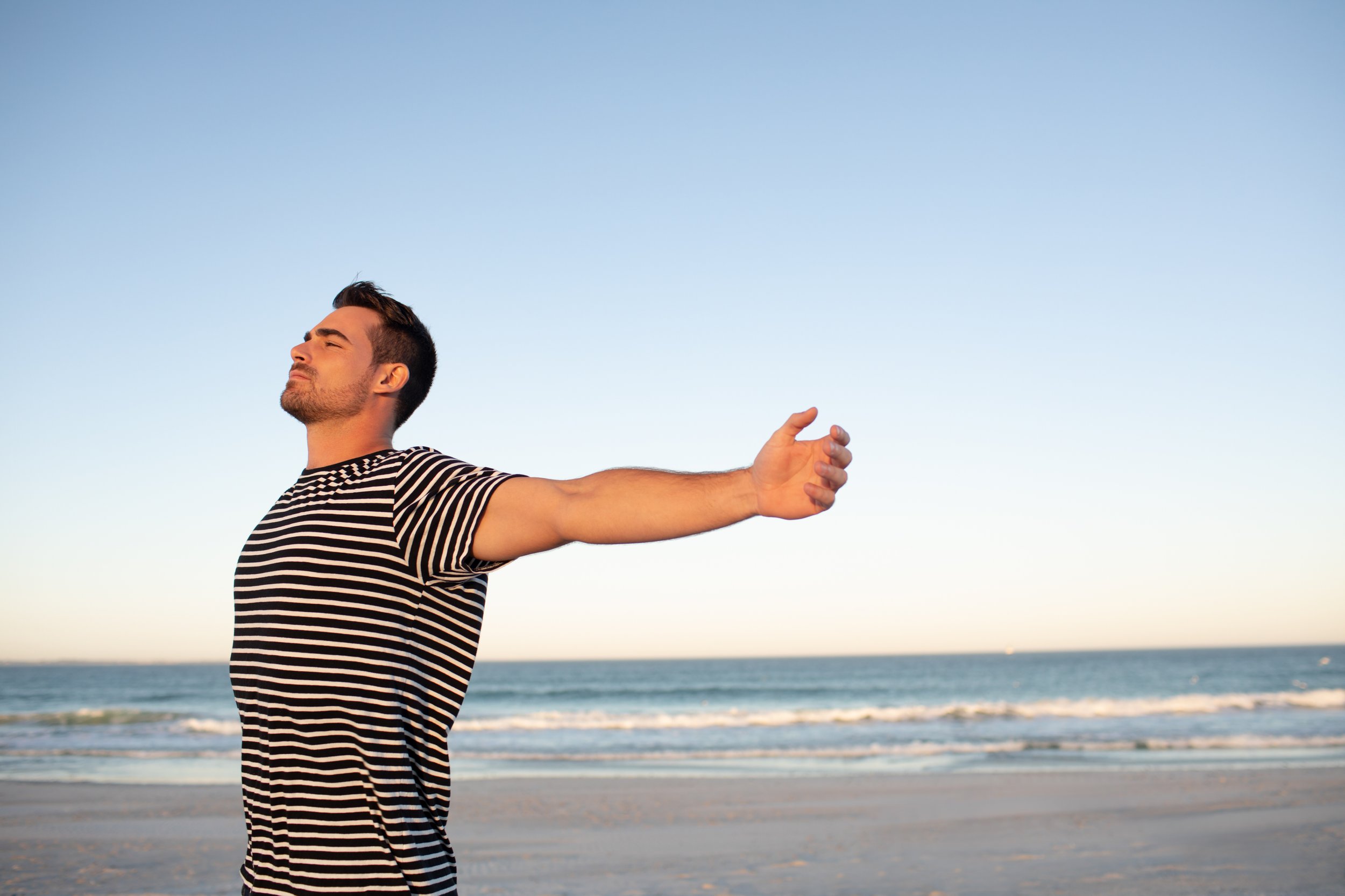 man-standing-with-arms-outstretched-beach.jpg
