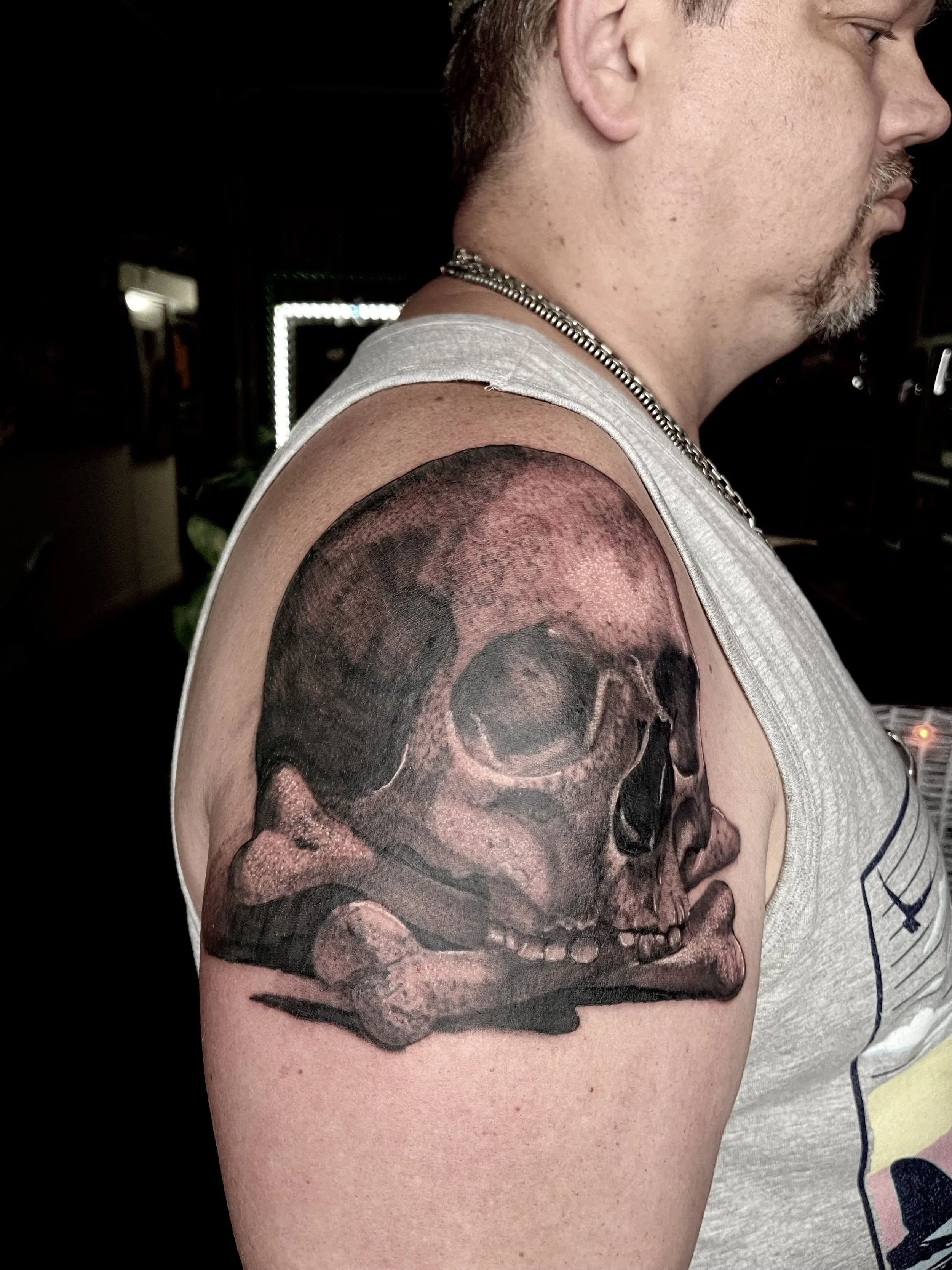 Tattoo of a skull with a crossbones design on the person's upper arm.