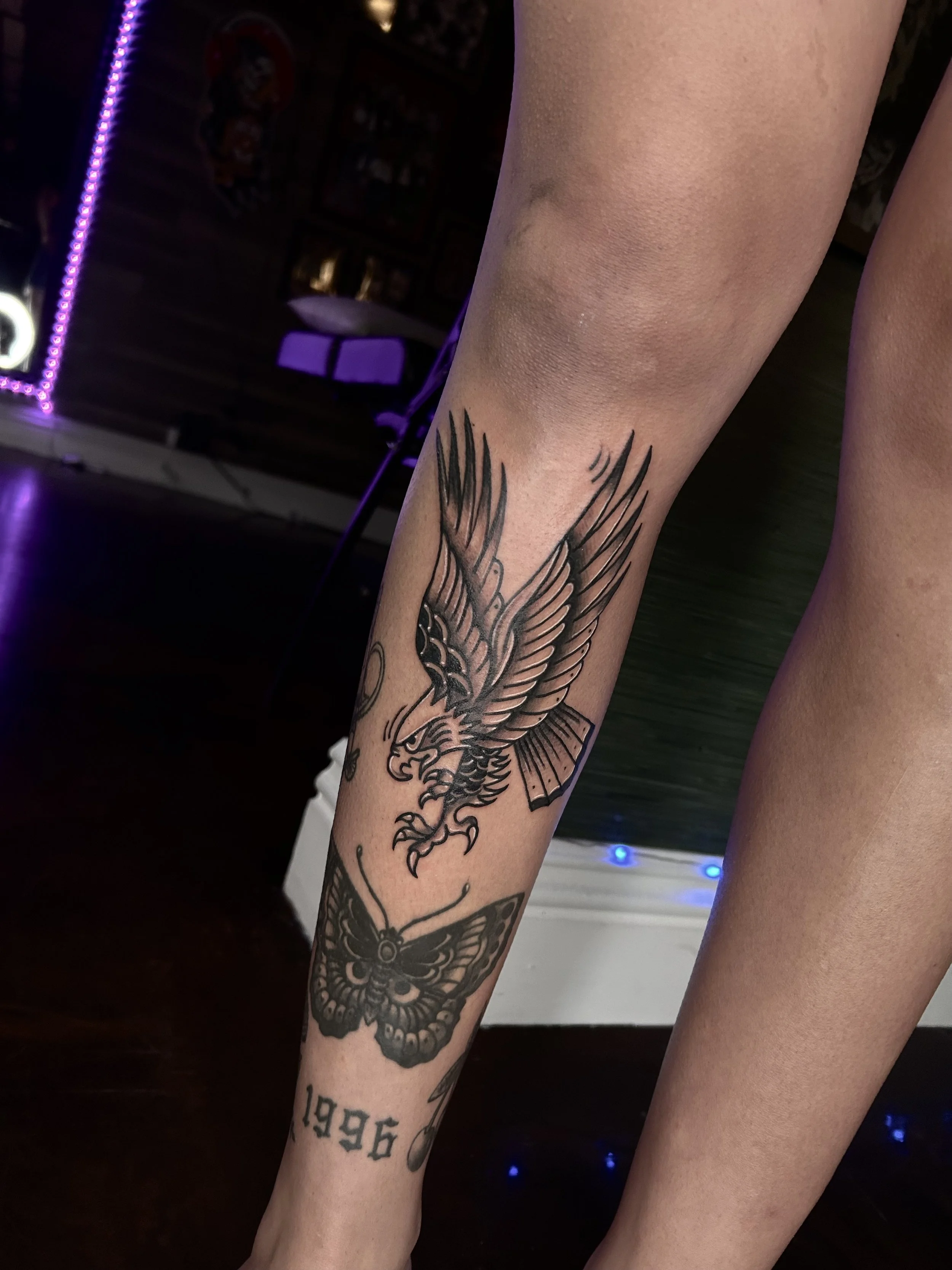 Tattoo of a fierce eagle and a moth on a person's lower leg, with the year '1996' tattooed below.