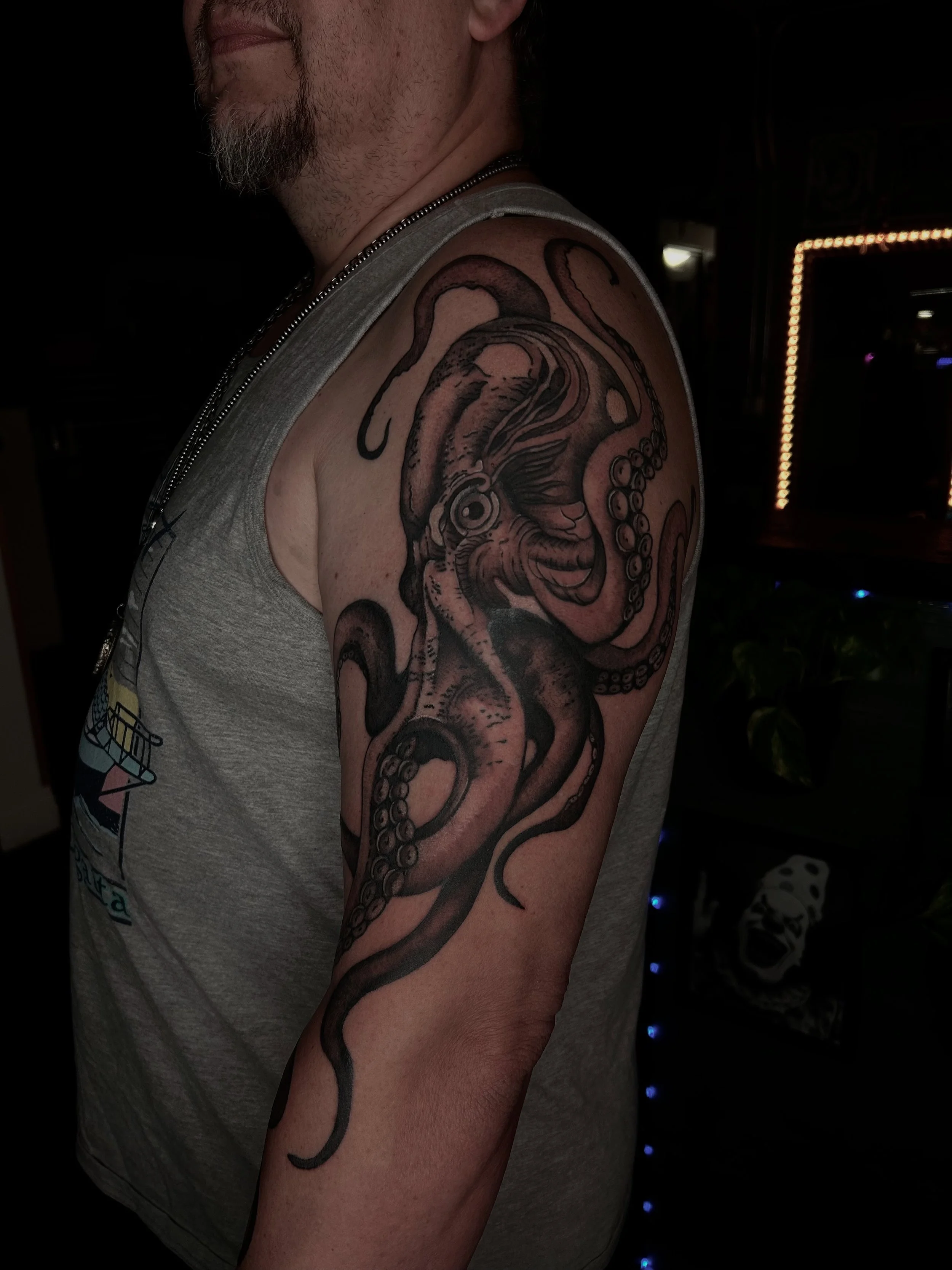 Tattoo of an octopus on a man's upper arm and shoulder.