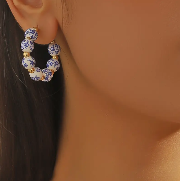 Elevate your everyday look with Mozzimo Jewelry’s blue and white porcelain beaded gold hoop earrings.