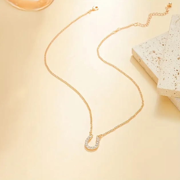 Add a touch of luck and luxury with the Gold Plated Mini White Gemstone Encrusted Horseshoe Pendant Charm Necklace from Mozzimo Jewelry.