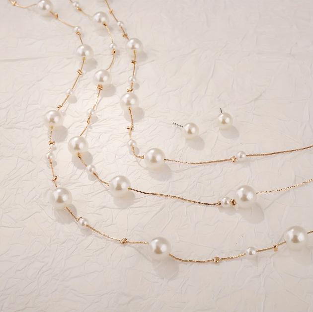 Drape yourself in elegance with Mozzimo Jewelry’s long triple-layer faux pearl necklace set — effortless glamor with modern layering appeal.