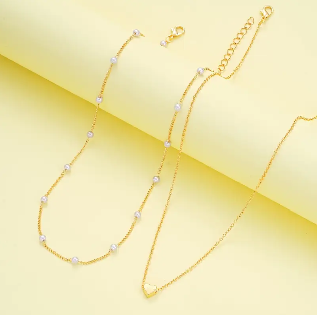 Shop the 2 Piece Gold Plated Double Layer Mini Pearls and Heart Charm Necklace and Bracelet Set at Mozzimo Jewelry—romantic, elegant, and perfect for any occasion!