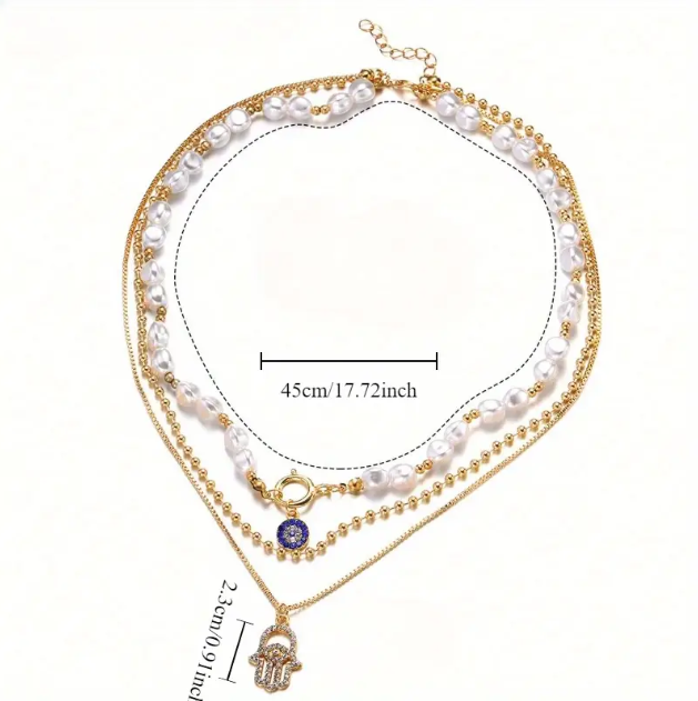 Elevate your look with this boho-chic gold plated triple layer necklace featuring pearls, beads, and a rhinestone Hamsa hand charm.
