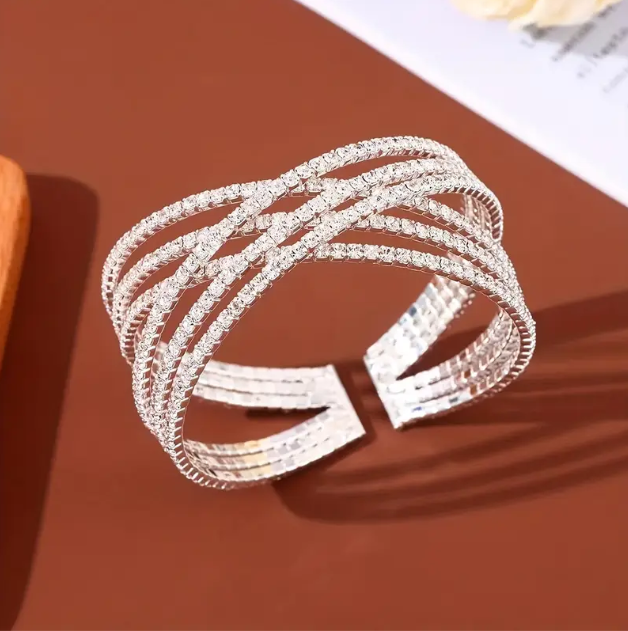 Shine bright with Mozzimo Jewelry's Silver Plated Rhinestone Encrusted Criss-Cross Open Cuff Bangle – a modern, elegant statement piece for any occasion.