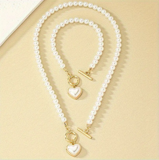 Add elegance to your style with the 2 Piece Gold Plated Faux Pearl Heart Pendant Choker Necklace and Bracelet Set from Mozzimo Jewelry. Shop now at www.mozzimojewelry.com.