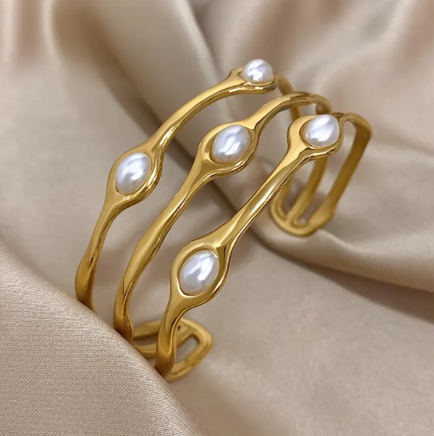 Elevate your wrist game with this gold-plated open cuff bracelet featuring layered baroque pearl accents.