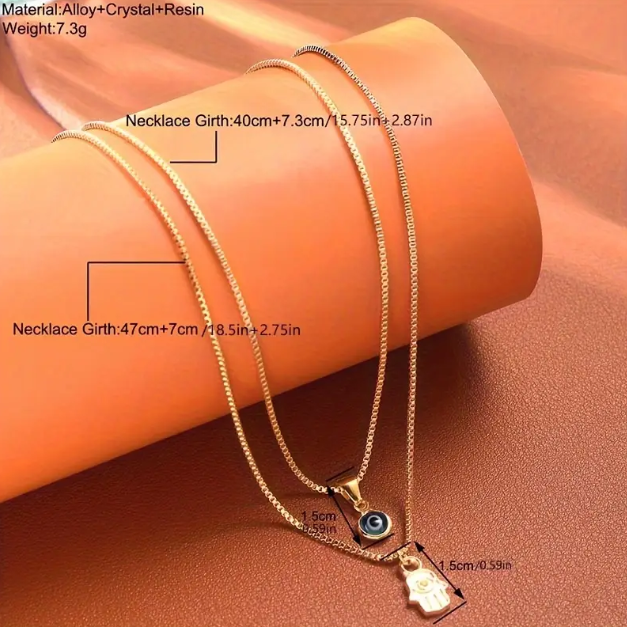 Embrace timeless protection and style with this Gold Plated Double Layer Evil Eye and Hamsa Hand Necklace from Mozzimo Jewelry.