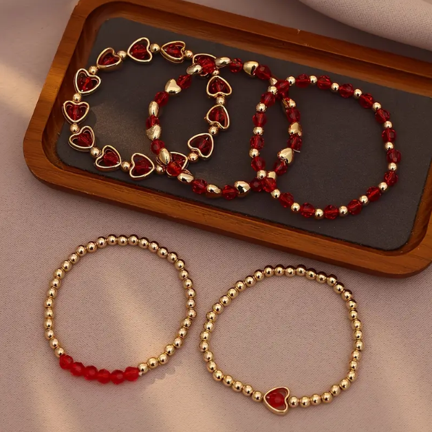 Add charm to your style with Mozzimo Jewelry’s 5 Piece Gold Plated Hearts and Charms Red Stackable Love Bracelet Set—layered gold and red bracelets—available now at www.mozzimojewelry.com.