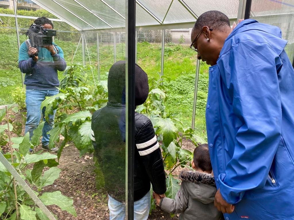 Cinematographer filming handheld during community garden documentary with children in the foreground