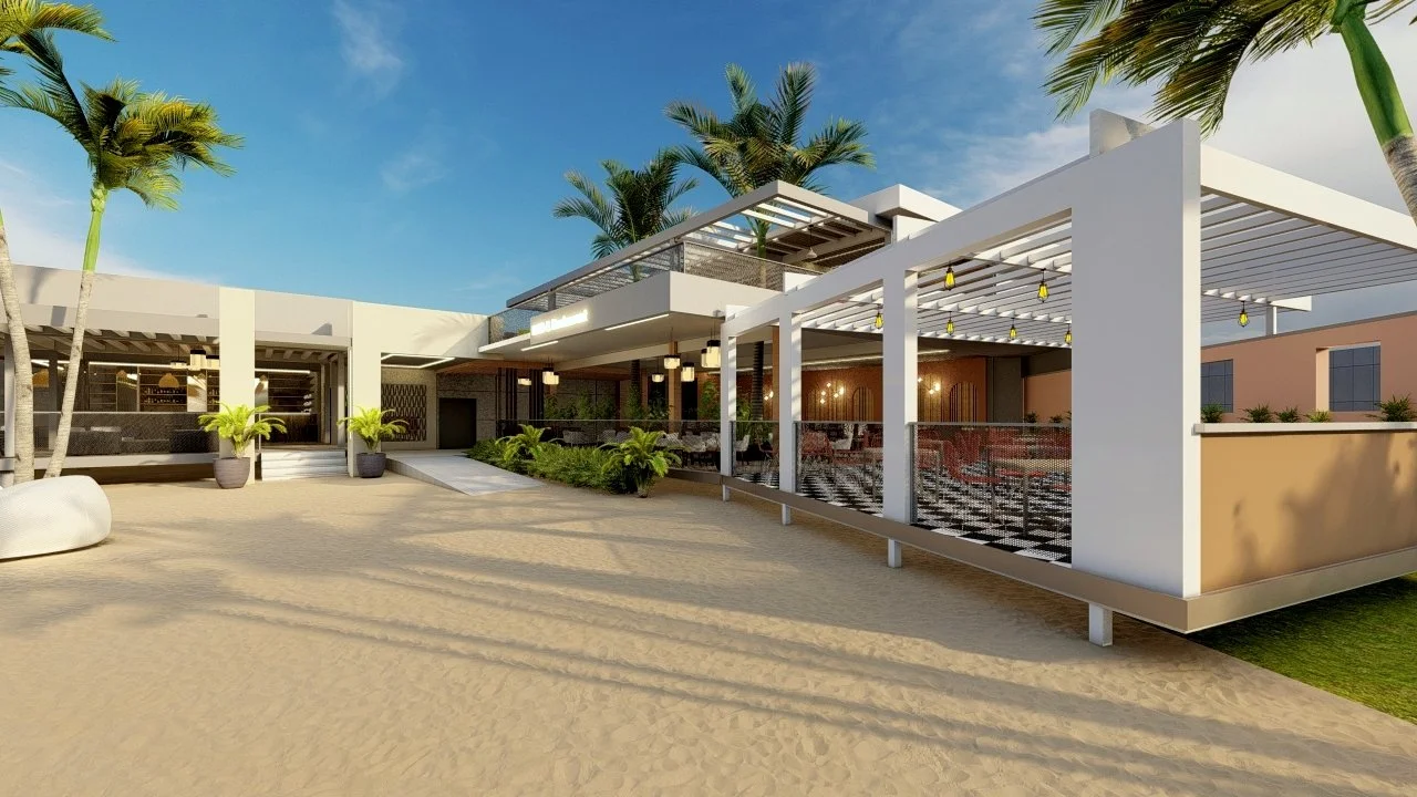 An outdoor view of a modern building with white and beige walls, surrounded by palm trees, on a sandy ground under a blue sky.