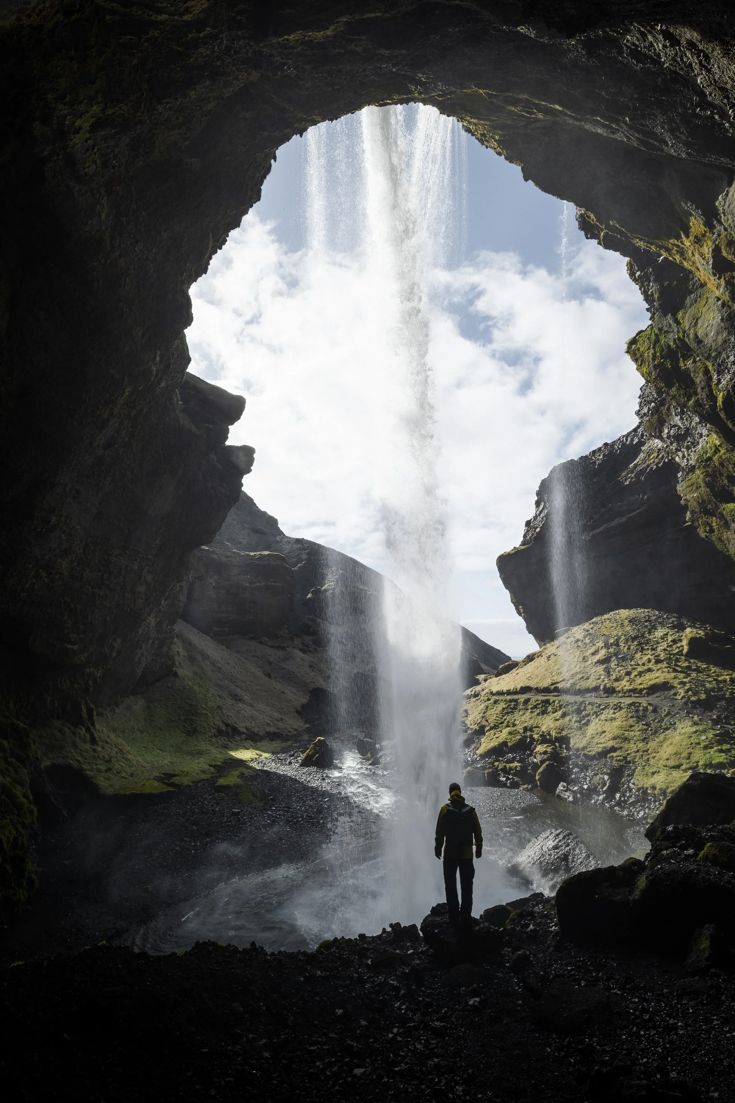 A spectator stands behind Kvernufuss - a waterfall that can be approached from behind