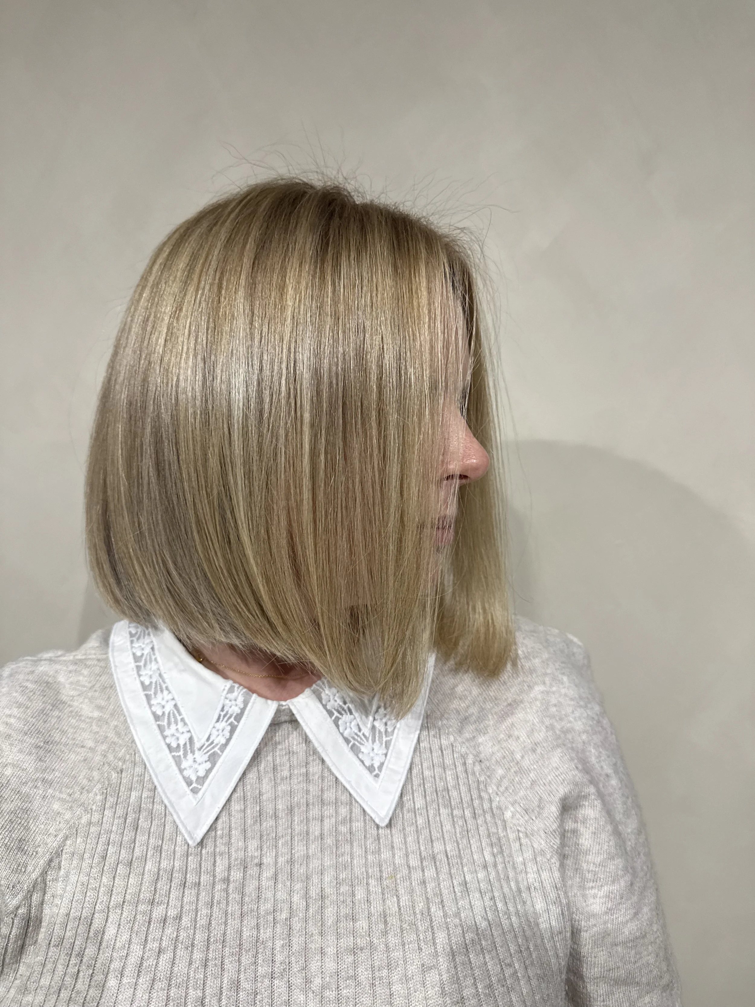 Back of a woman with long, wavy, blonde hair sitting in a salon chair.