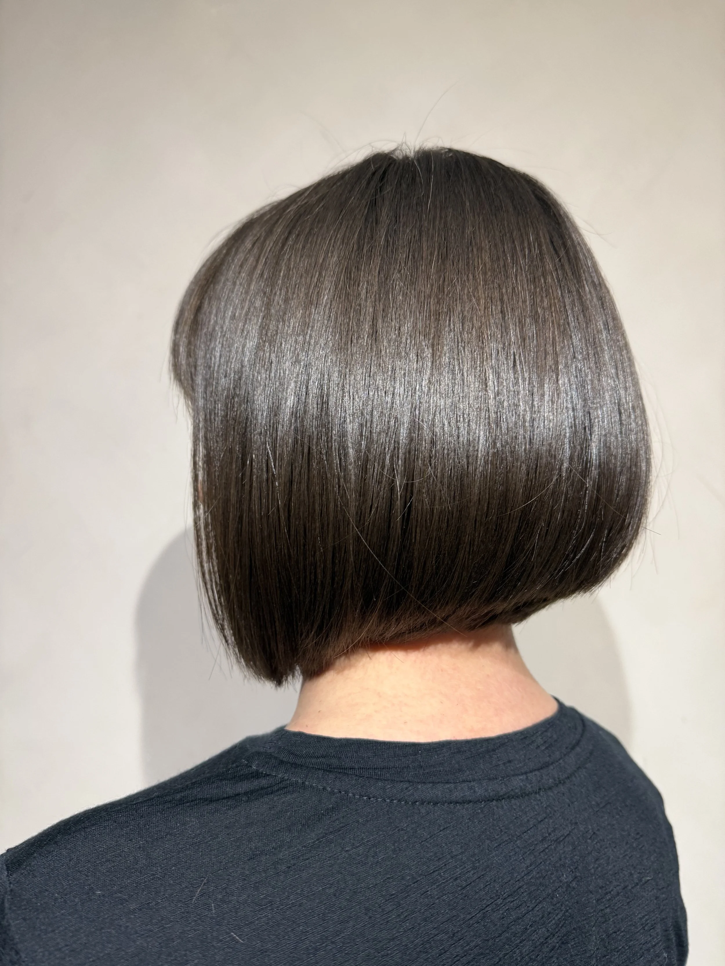 Side view of a person with shoulder-length, wavy, dark hair in a hair salon.