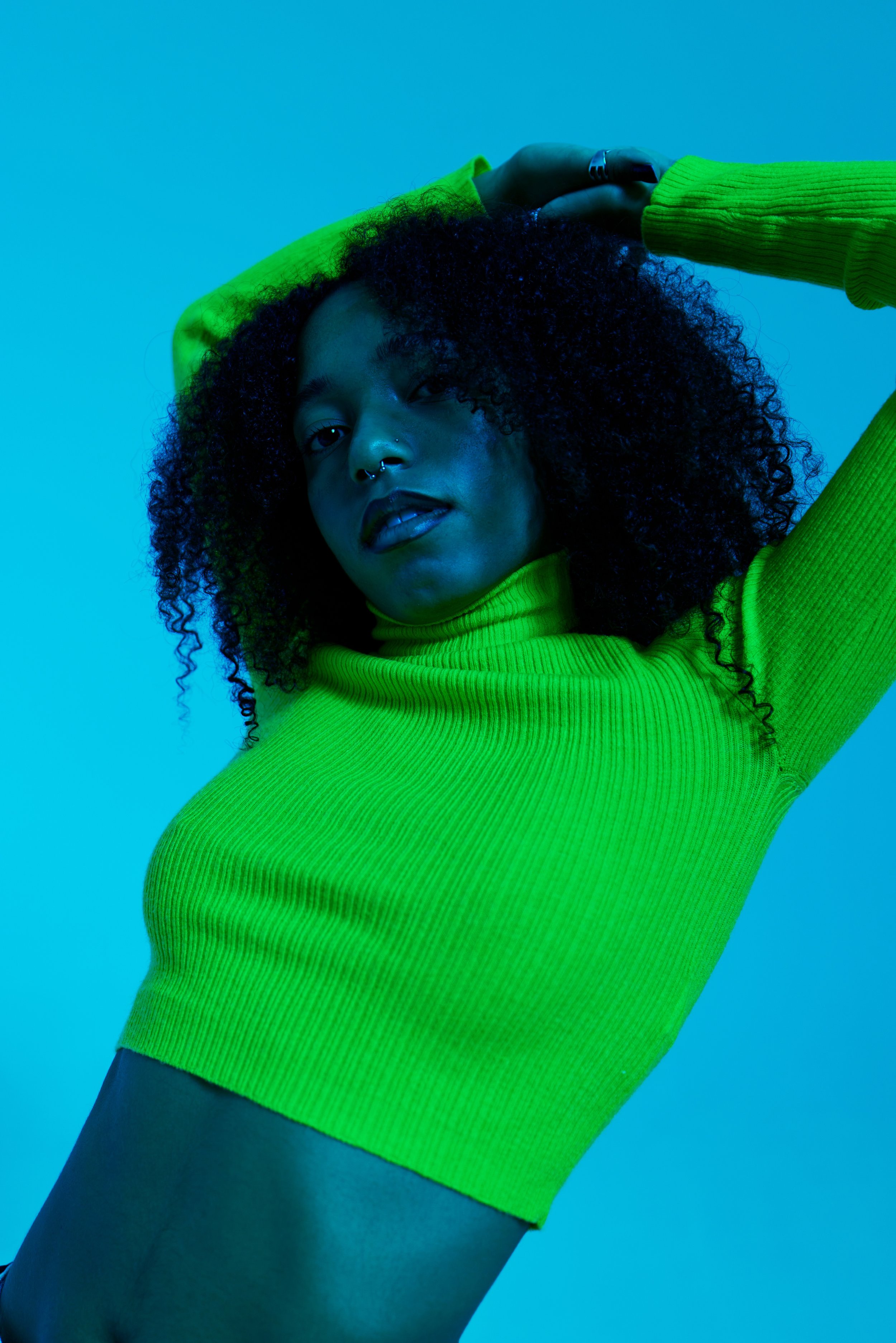 Artista donna con un maglione verde su sfondo blu