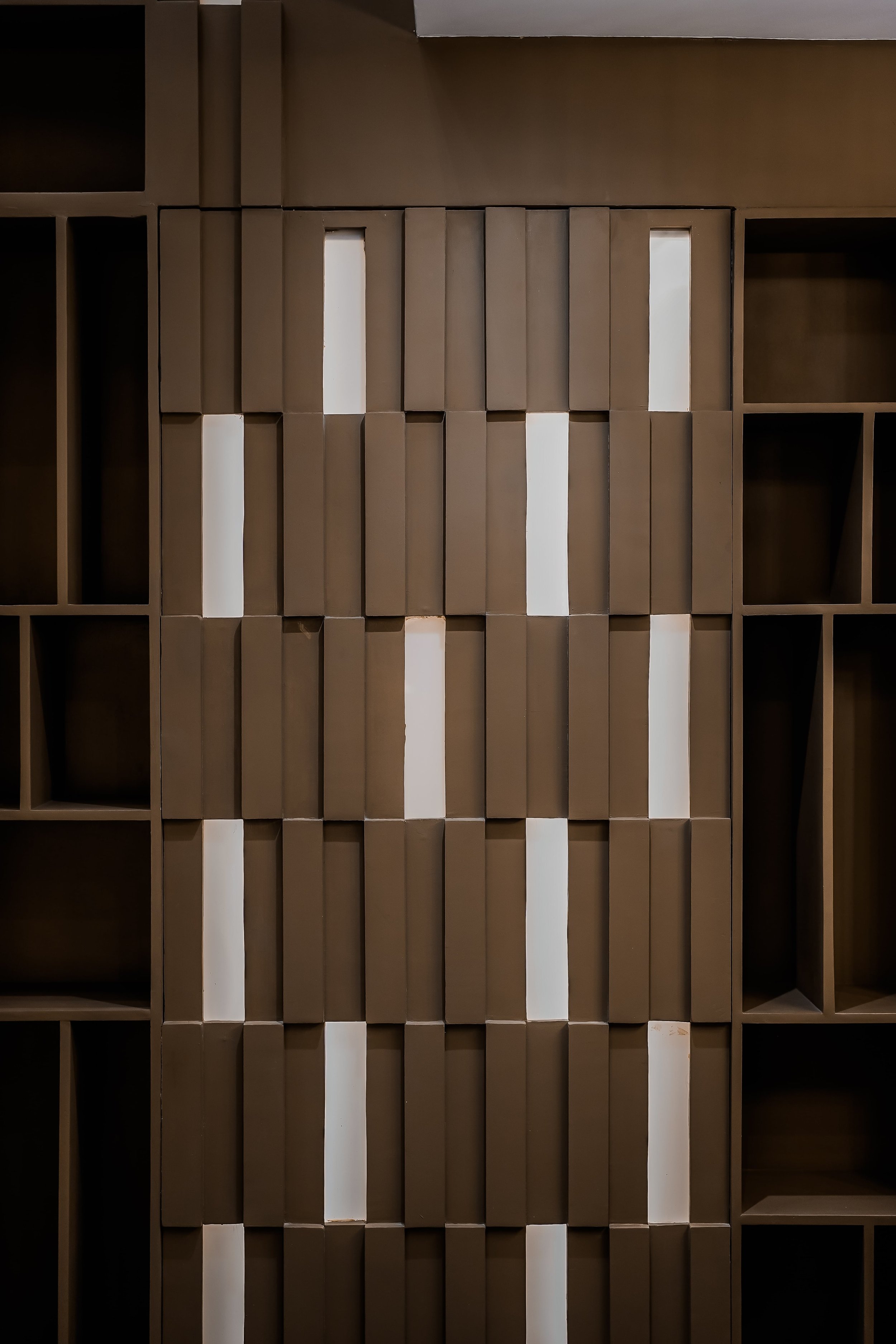 Brown geometric patterned wall with rectangular panels and vertical white gaps, creating a textured appearance.