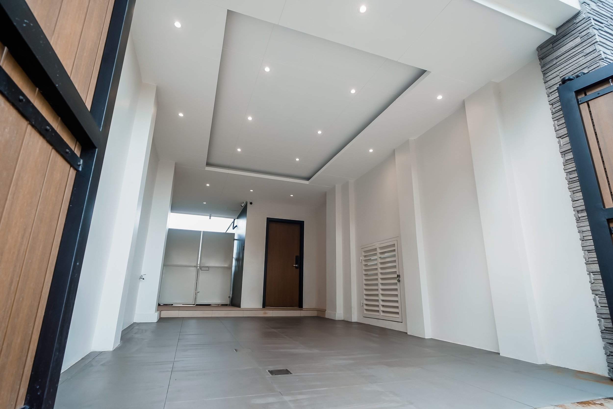 Modern empty garage with recessed lighting, clean white walls, and a wooden door.