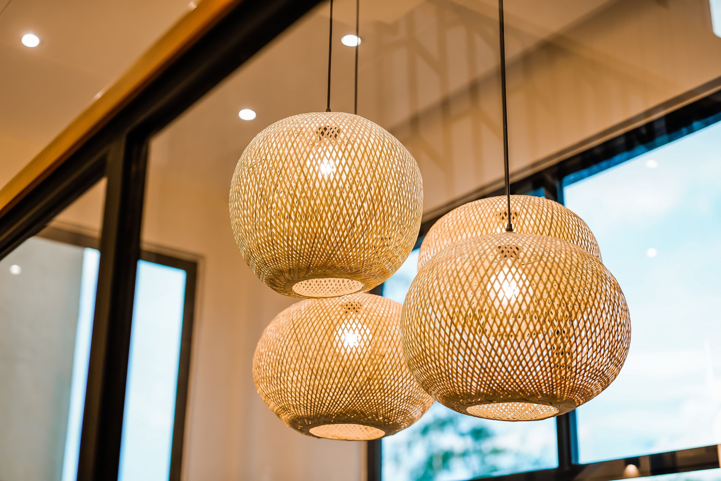 Hanging woven pendant lights with a reflective ceiling and windows.