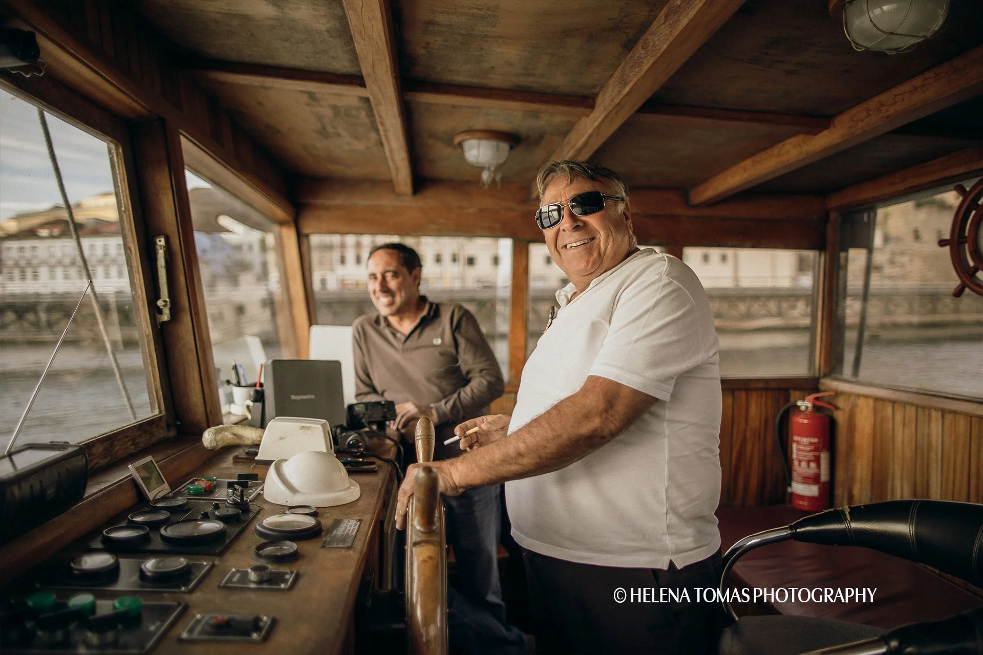 Smiling captains steering a traditional Rabelo boat on the Douro River in Porto