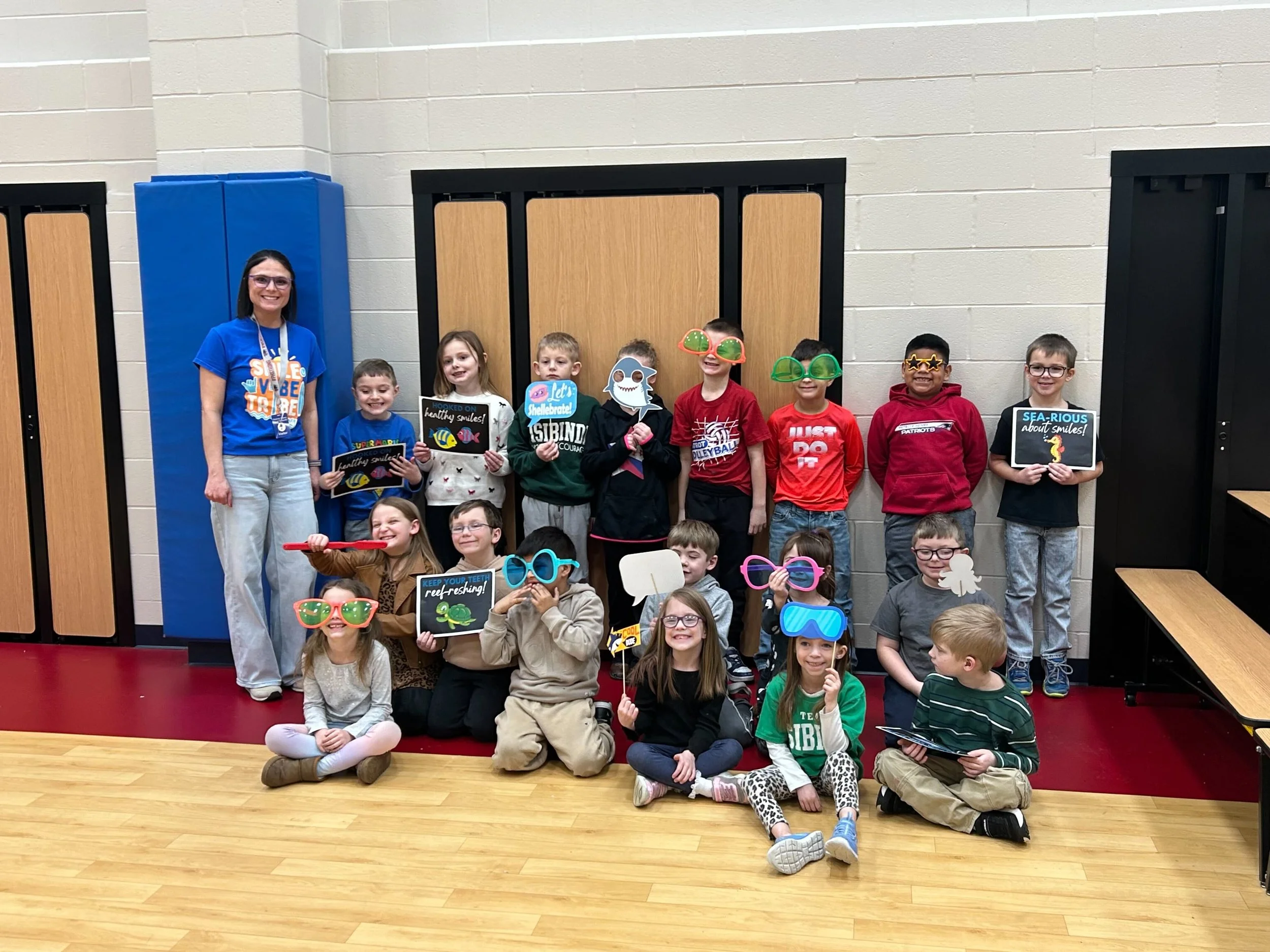 All About Kids Pediatric Dentistry team member and elementary school students celebrating National Children's Dental Health Month with fun photo props