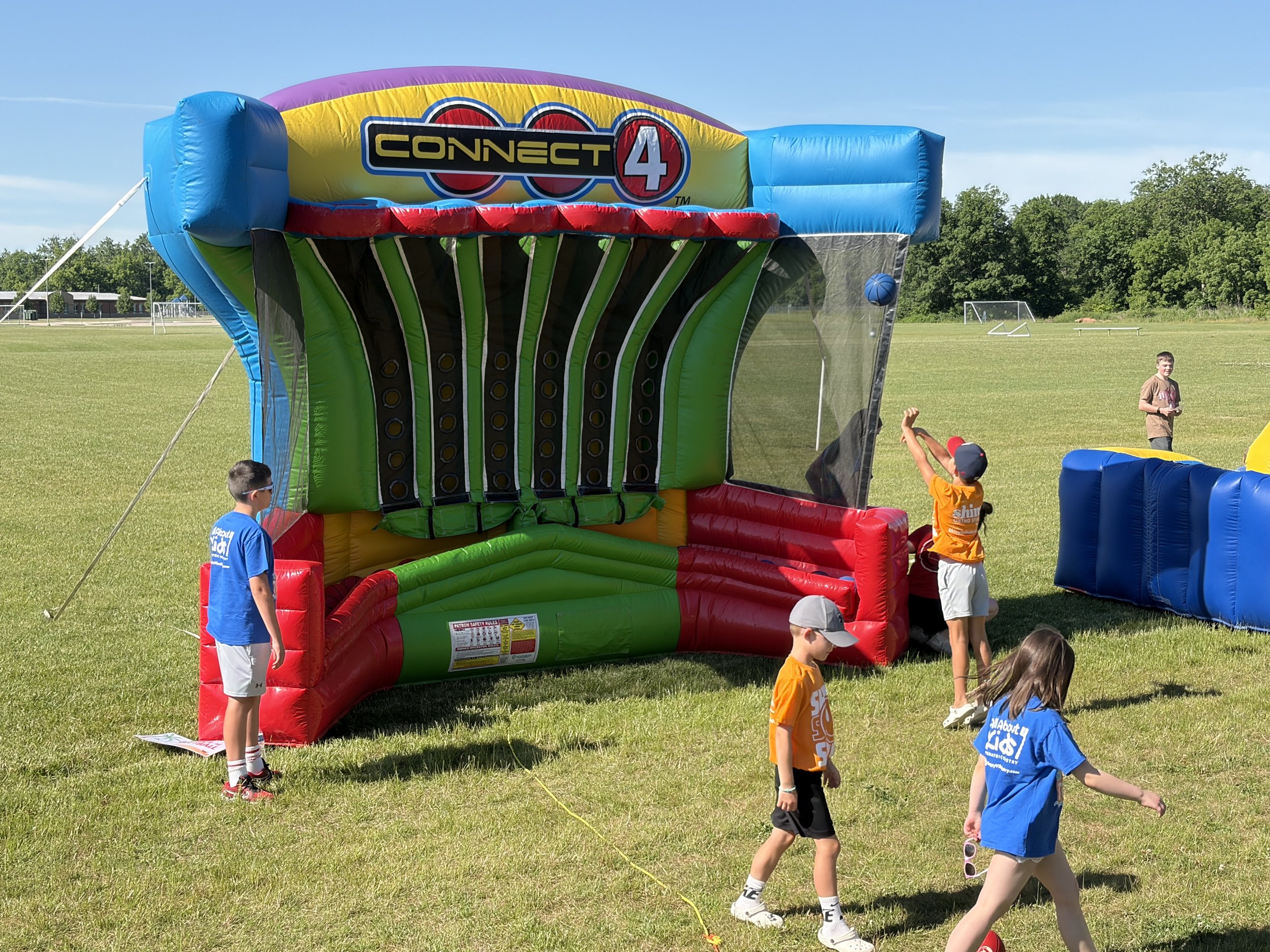 Kids playing on a giant Connect Four inflatable during the All About Kids Pediatric Dentistry Family Fun Day.