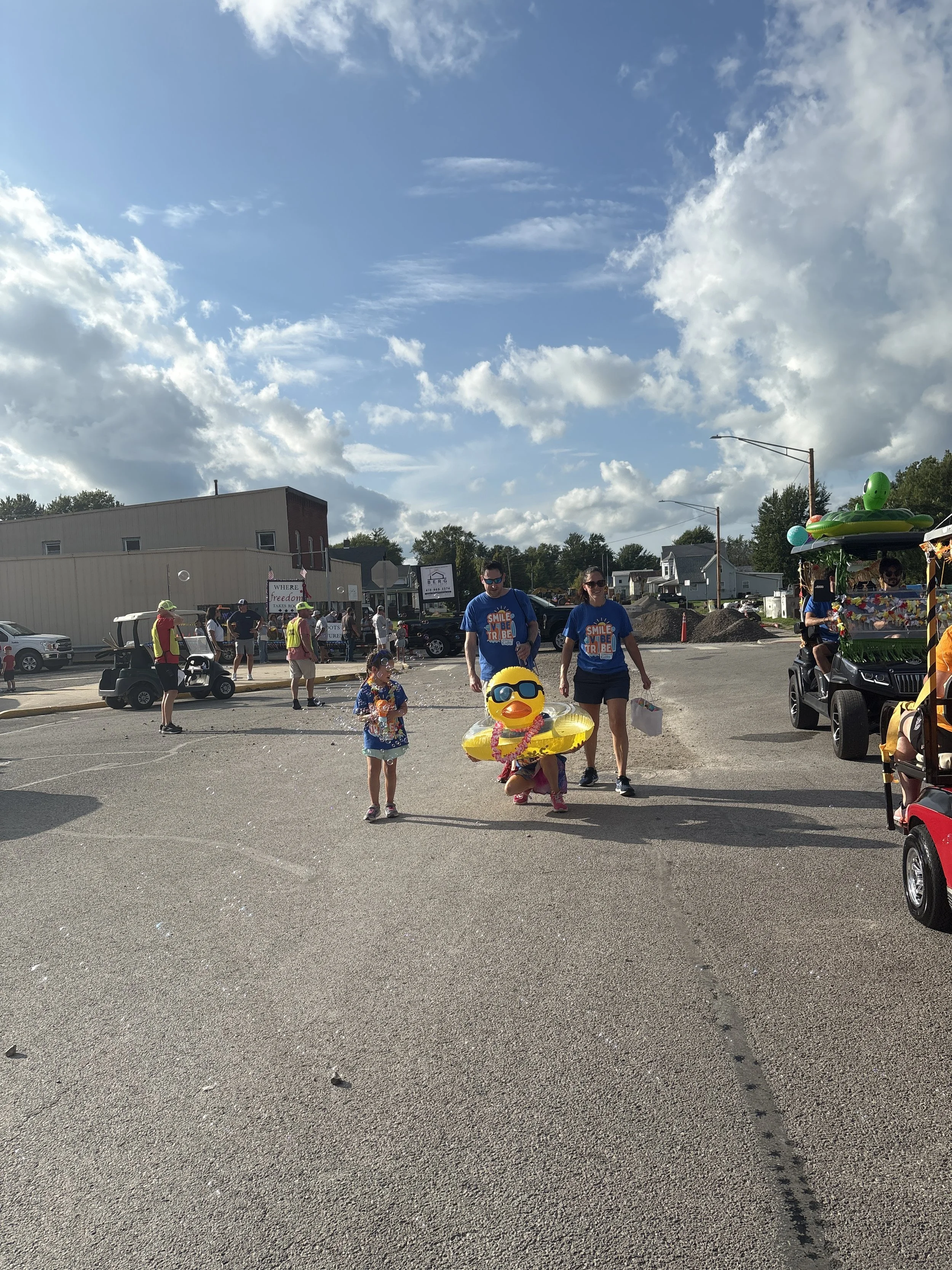 All About Kids Pediatric Dentistry team members walking in the Henry County Parade holding a large yellow duck prop in Napoleon, Ohio.