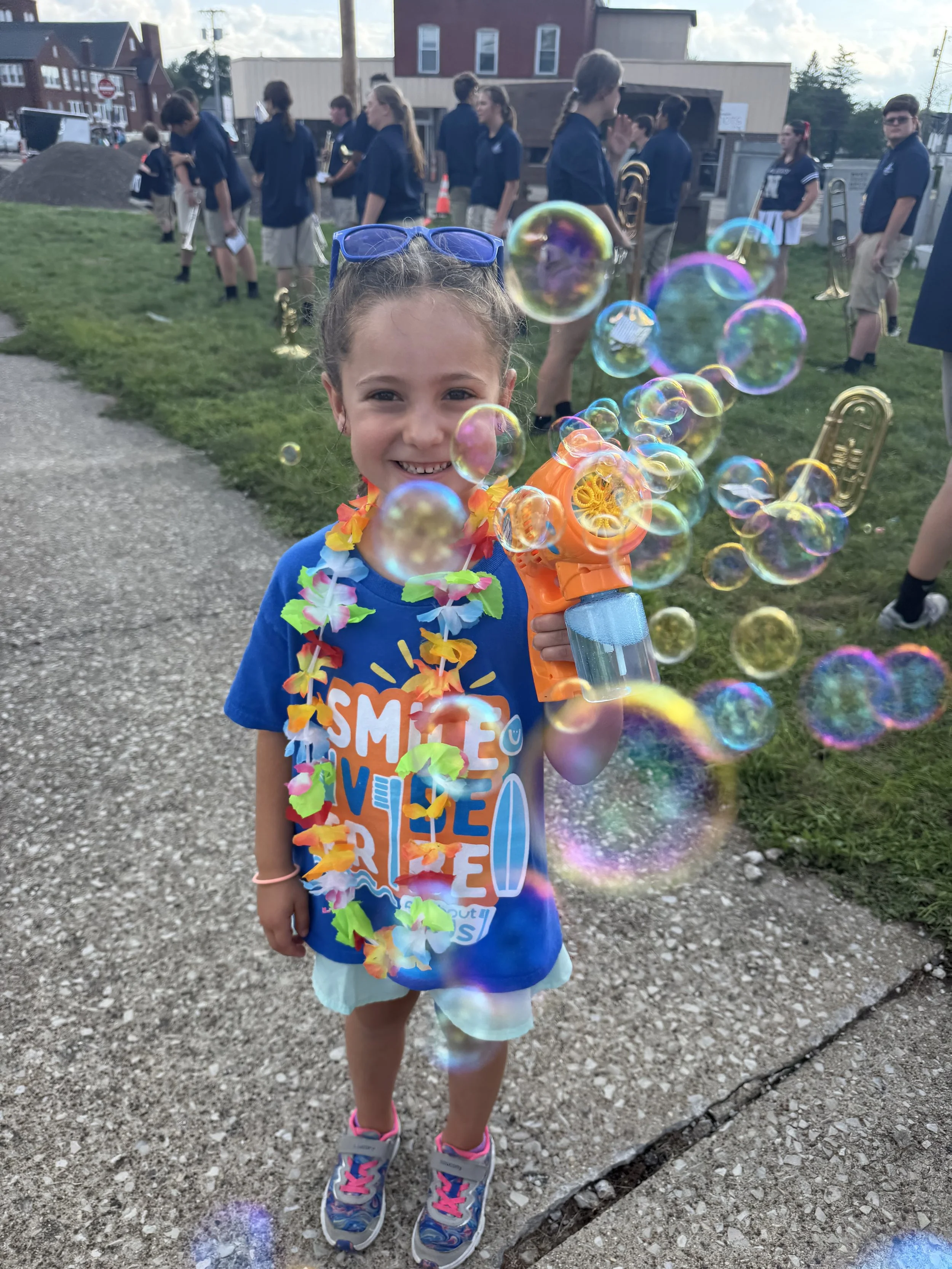 Young girl smiling and blowing bubbles while watching the Henry County Parade in Napoleon, Ohio.