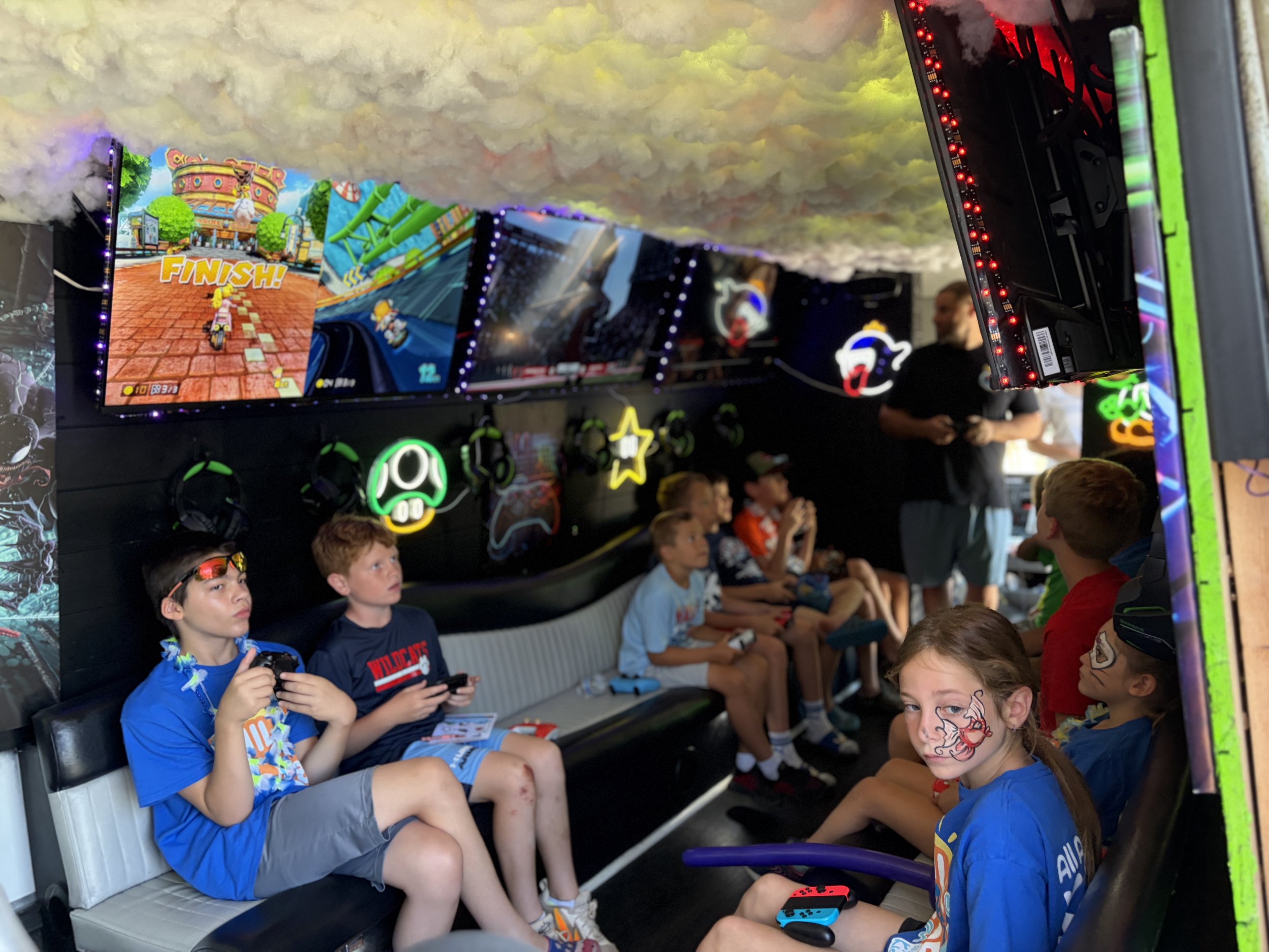 Children enjoying multiplayer video games inside the gaming truck at the All About Kids Pediatric Dentistry Family Fun Day.