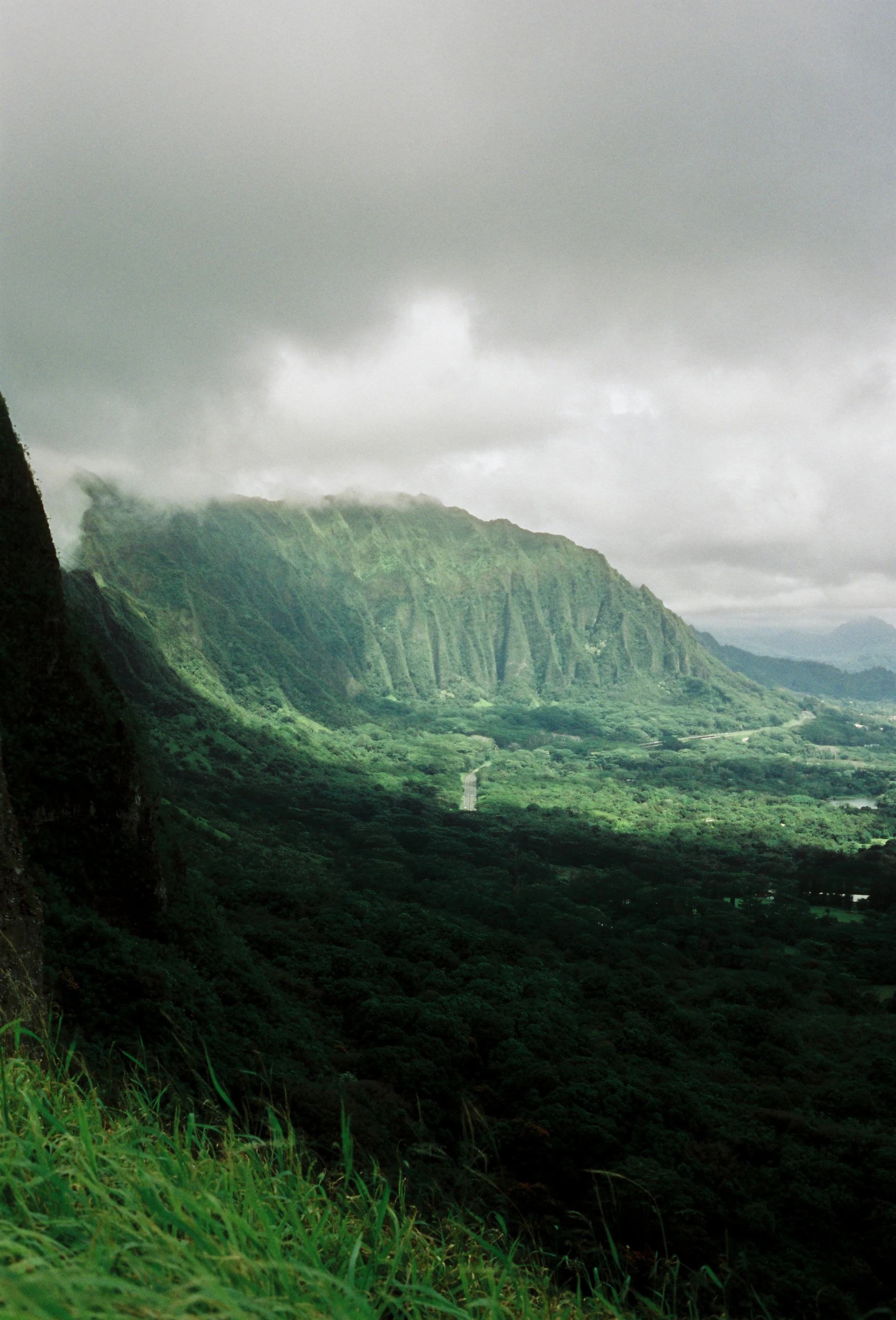 A lush green mountain landscape with a cloudy sky overhead.